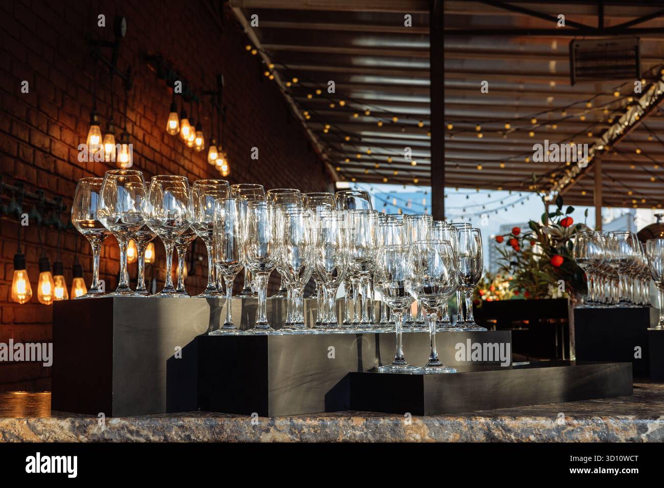 Eleganti oggetti in vetro disposti in file sotto la luce dorata, perfetti per eventi di lusso, marchi da bar o immagini minimaliste per l'ospitalità. Foto Stock