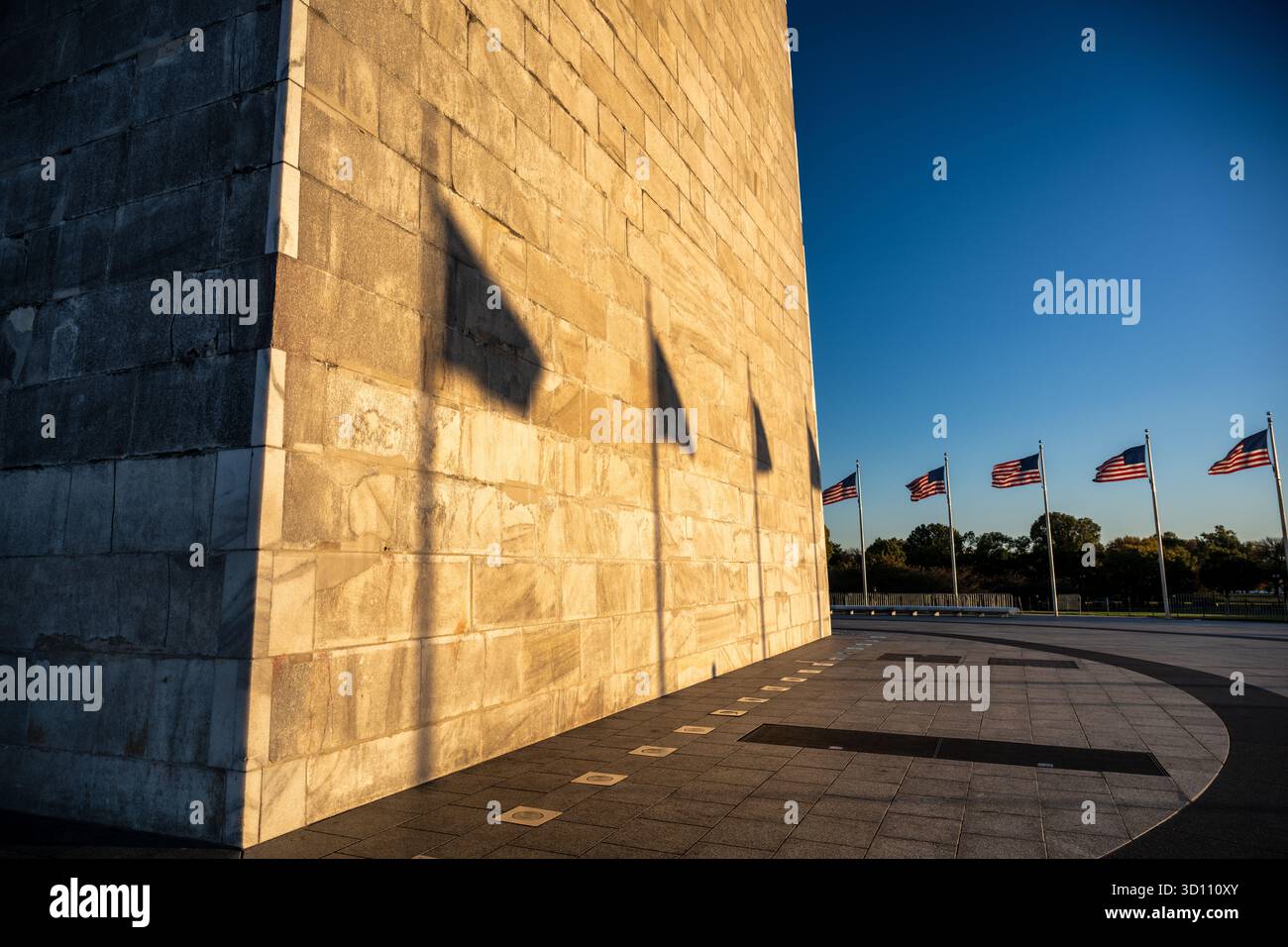 Monumento a Washington con le ombre della bandiera al tramonto Washington DC // WASHINGTON DC - la facciata in marmo del monumento a Washington è bagnata dal sole basso che tramonta, gettando lunghe ombre delle bandiere americane sulla sua superficie. Questo iconico obelisco, in onore del primo presidente degli Stati Uniti George Washington, è un importante punto di riferimento nel National Mall. È la struttura in pietra più alta del mondo e l'obelisco, alto 169,29 metri (555 piedi e 5 pollici). Foto Stock