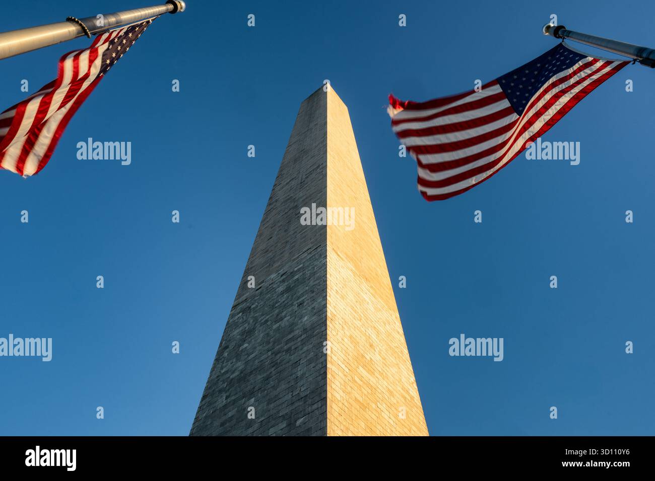 Monumento a Washington con bandiere americane al tramonto Washington DC // WASHINGTON DC - il monumento a Washington, un obelisco di spicco, è incorniciato da due bandiere americane. Questa struttura iconica commemora George Washington, il primo presidente degli Stati Uniti. È l'obelisco più alto del mondo, alto 169,29 metri (555 piedi 5 1/8 pollici). Costruito in marmo, granito e gneiss di pietra blu, il monumento è stato completato nel 1884 e rimane una caratteristica centrale del National Mall a Washington DC. Foto Stock