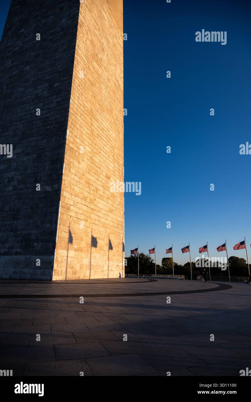 Monumento a Washington con il tramonto del sole e la bandiera delle ombre Washington DC // WASHINGTON DC - il monumento a Washington è illuminato dal sole che tramonta, proiettando ombre distinte delle bandiere americane sulla sua facciata in pietra. Questo iconico obelisco, situato sul National Mall, onora George Washington, il primo presidente degli Stati Uniti. Alto 169,29 metri (555 piedi e 5 pollici), è la struttura in pietra e l'obelisco più alti del mondo. La costruzione iniziò nel 1848 e fu completata nel 1884, con la sua dedica nel 1885. Il monumento è gestito dal National Park Service ed è un punto di riferimento centrale nella cap della nazione Foto Stock