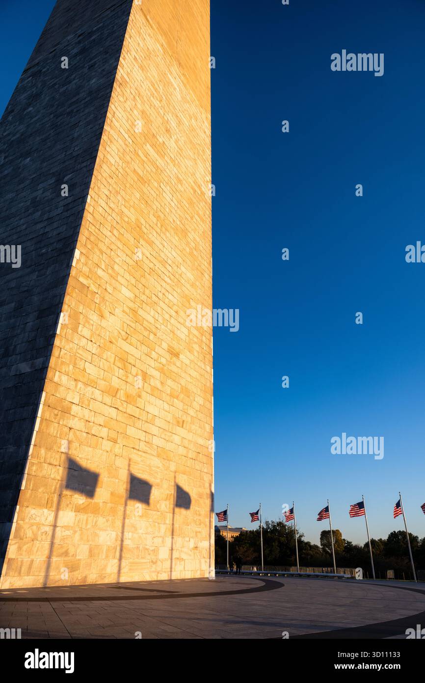 Monumento a Washington con le ombre della bandiera al tramonto Washington DC // WASHINGTON DC - il monumento a Washington è illuminato dal sole che tramonta, gettando lunghe ombre delle bandiere americane sulla sua facciata in pietra dalle tonalità dorate. Questo iconico obelisco, costruito in marmo, granito e gneiss di pietra blu, è alto 169,29 metri (555 piedi e 1/8 pollici). Le bandiere fanno parte del "Ring of Flags" che circonda il monumento, in onore del primo presidente degli Stati Uniti, George Washington. E' un importante punto di riferimento sul National Mall. Foto Stock