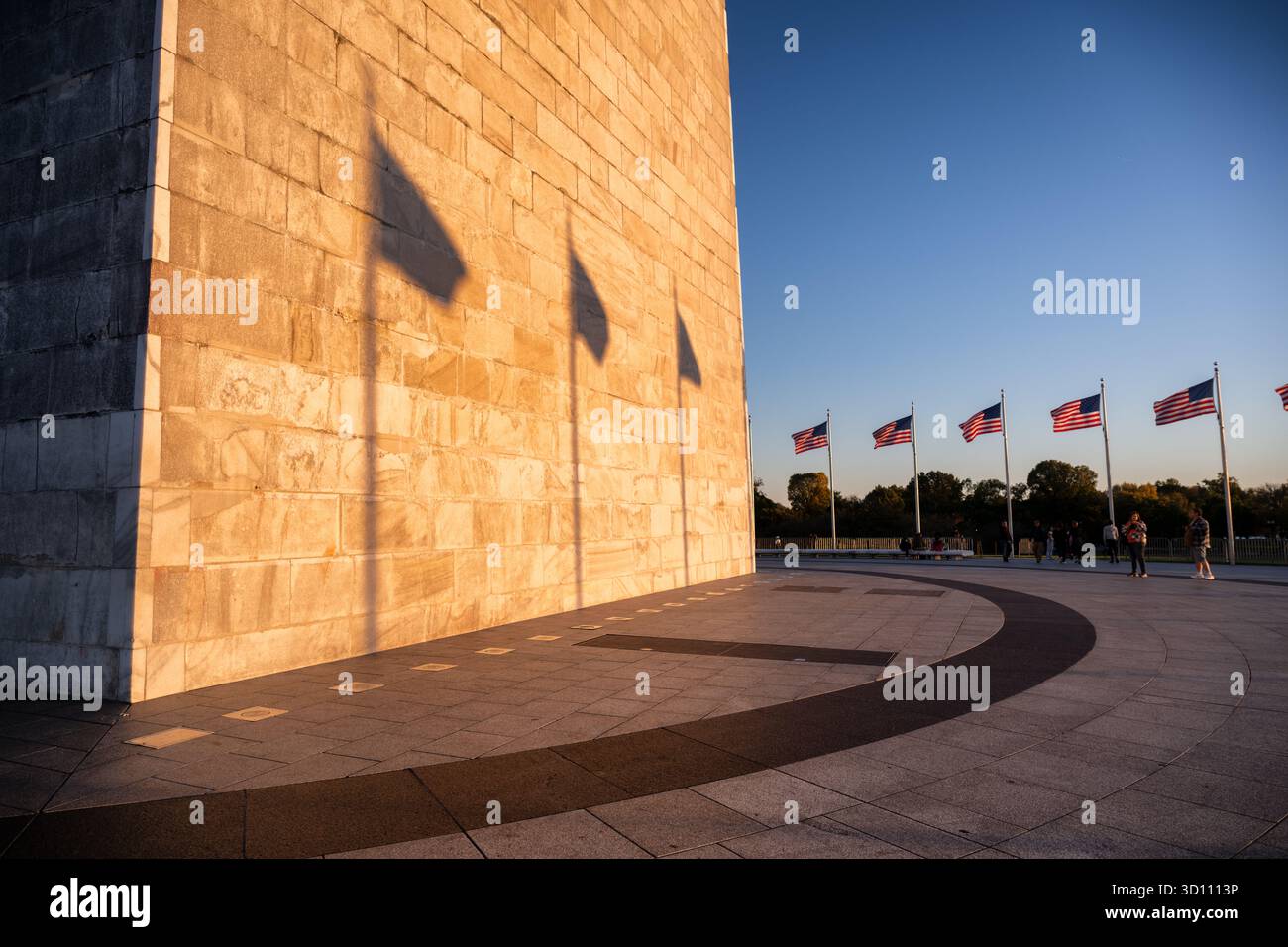 Washington Monument Flag Shadows Setting Sun Washington DC // WASHINGTON DC - il Washington Monument è illuminato dal sole che tramonta, proiettando ombre prominenti delle bandiere americane sulla sua facciata in pietra. Questo iconico obelisco, dedicato a George Washington, è costruito principalmente in marmo, granito e gneiss di pietra blu. Alto 169,294 metri (555 piedi e 1/8 pollici), è l'obelisco più alto del mondo e una caratteristica prominente del National Mall. Gestito dal National Park Service, questo importante monumento nazionale è un potente simbolo della storia americana e del patriottismo dei nati Foto Stock