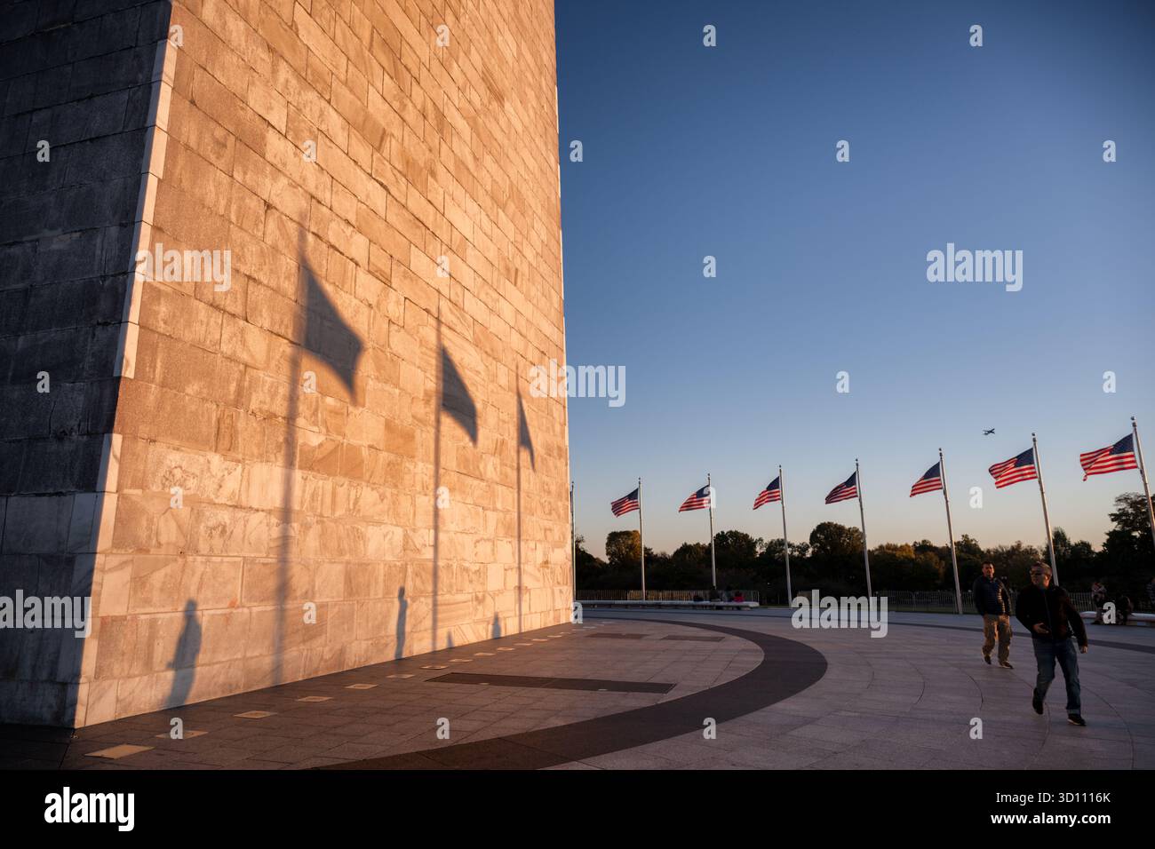 Monumento a Washington con le ombre della bandiera al tramonto Washington DC // WASHINGTON DC - il monumento a Washington è bagnato da un bagliore dorato del sole che tramonta, gettando ombre distinte delle bandiere americane sulla sua facciata in pietra. Questo iconico obelisco, costruito per commemorare George Washington, è costruito in marmo, granito e gneiss di pietra blu. Si erge a 169,046 metri (554 piedi e 7 pollici) di altezza, rendendolo la struttura in pietra più alta del mondo e l'obelisco più alto del mondo. Un anello di 50 bandiere americane circonda questa caratteristica centrale del National Mall di Washington DC. Foto Stock