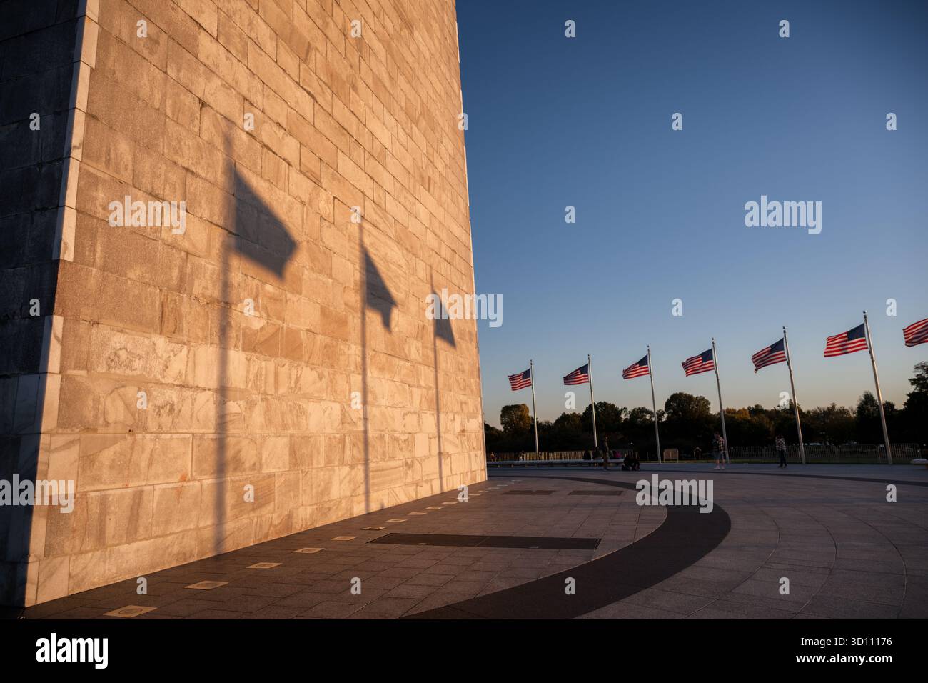 Monumento a Washington con le ombre della bandiera al tramonto Washington DC // WASHINGTON DC - il monumento a Washington si illumina al tramonto, gettando le ombre delle bandiere americane sulla sua facciata in pietra. Questo obelisco, costruito in marmo, granito e gneiss di pietra blu, è alto 169,294 metri (555 piedi e 1/8 pollici). Situato sul National Mall, commemora George Washington, il primo presidente degli Stati Uniti, ed è stato completato nel 1884 e dedicato nel 1885. Foto Stock