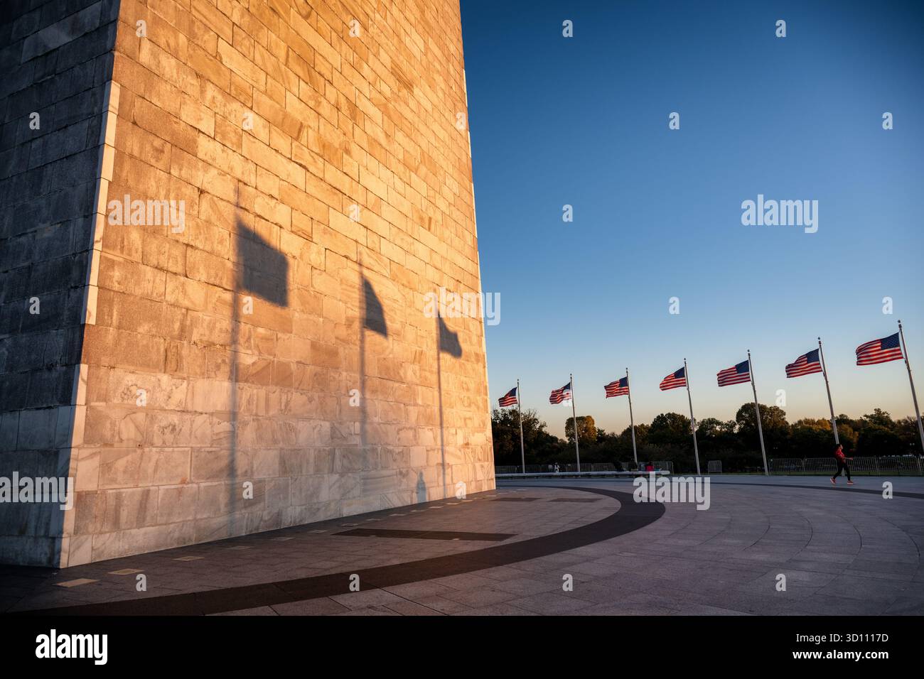 Monumento a Washington con bandiere americane al tramonto Washington DC // WASHINGTON DC - il monumento a Washington è immerso nel bagliore dorato del sole che tramonta, gettando lunghe ombre delle bandiere americane sulla sua superficie di marmo e granito. Questo iconico obelisco, alto 555 piedi e 1/8 cm, è una caratteristica importante del National Mall. Dedicato nel 1885, commemora George Washington, il primo presidente degli Stati Uniti, ed è gestito dal National Park Service. Foto Stock