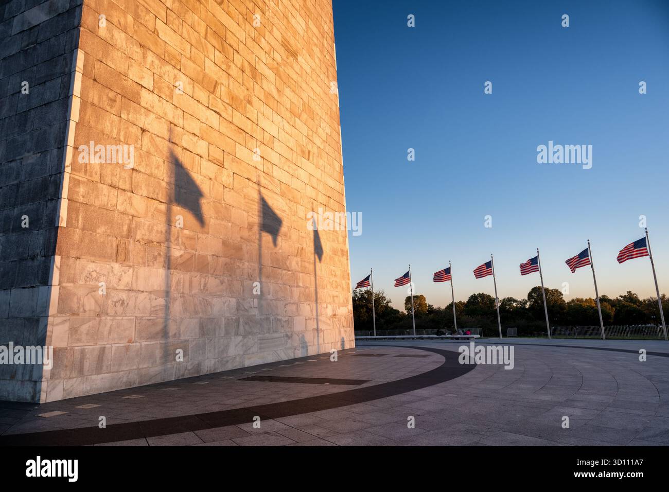 Monumento a Washington con le ombre della bandiera al tramonto Washington DC // WASHINGTON DC - il monumento a Washington è bagnato dalla luce dorata del sole che tramonta, gettando ombre distinte delle bandiere americane sulla sua facciata in pietra. Questo obelisco di spicco, costruito in marmo, granito e gneiss di pietra blu, commemora George Washington. Alto 169,294 metri (555 piedi e 1/8 pollici), è una caratteristica centrale del National Mall e un simbolo riconosciuto a livello mondiale della storia e dell'ingegno americani. Amministrato dal National Park Service, rimane uno dei luoghi di interesse più visitati della uni Foto Stock