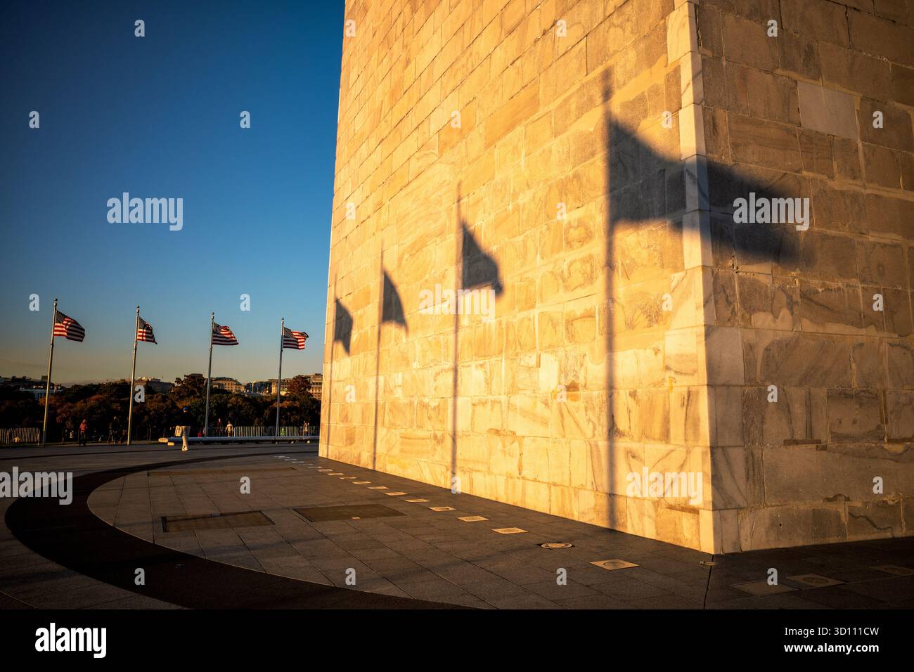 Il Washington Monument cattura la luce dorata del sole prima del tramonto Washington DC // WASHINGTON DC — il Washington Monument, un obelisco di spicco, è illuminato dalla luce del sole bassa, gettando le ombre delle bandiere americane sulla sua facciata in marmo. Questo monumento nazionale commemora George Washington, il primo presidente degli Stati Uniti. Alto 555 piedi 1/8 pollici (169,29 metri), il monumento è una caratteristica centrale del National Mall, costruito in marmo bianco, granito e gneiss di pietra blu tra il 1848 e il 1884. Foto Stock
