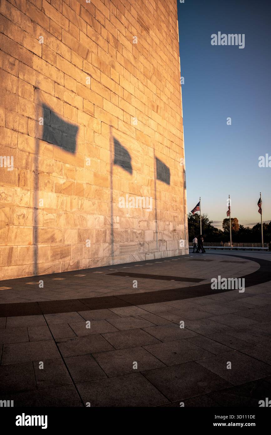 Washington Monument Golden Hour Light Washington DC // WASHINGTON DC - il Washington Monument è immerso nella calda luce dell'ora d'oro, che getta le ombre delle bandiere americane sulla sua facciata in marmo e granito. Questo iconico obelisco, alto 169,294 metri (555 piedi e 1/8 pollici), è la struttura in pietra più alta del mondo e l'obelisco più alto del mondo. Serve come memoriale a George Washington, il primo presidente degli Stati Uniti. Situato sul National Mall, questo importante punto di riferimento nella capitale della nazione è stato costruito tra il 1848 e il 1884 ed è gestito dal National Park Serv Foto Stock