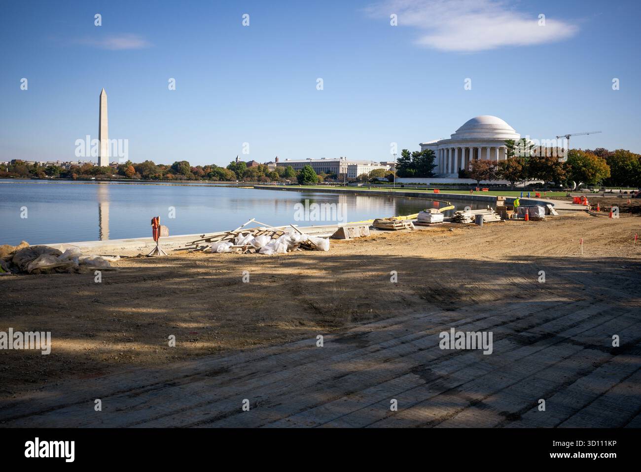 Tidal Basin Seawall Reconstruction Project Progress Washington DC // WASHINGTON DC — Progress on the Tidal Basin Seawall Reconstruction Project è visibile il 24 ottobre 2025, con il Washington Monument e Jefferson Memorial sullo sfondo. Questo ampio progetto affronta i problemi infrastrutturali critici, come il cedimento e le inondazioni marittime quotidiane che interessano i diapason storici. Il National Park Service sta effettuando la ricostruzione per proteggere questi iconici monumenti e il parco circostante. I materiali e le attrezzature da costruzione sono presenti lungo il bordo del bacino, a indicare che sono in corso Foto Stock