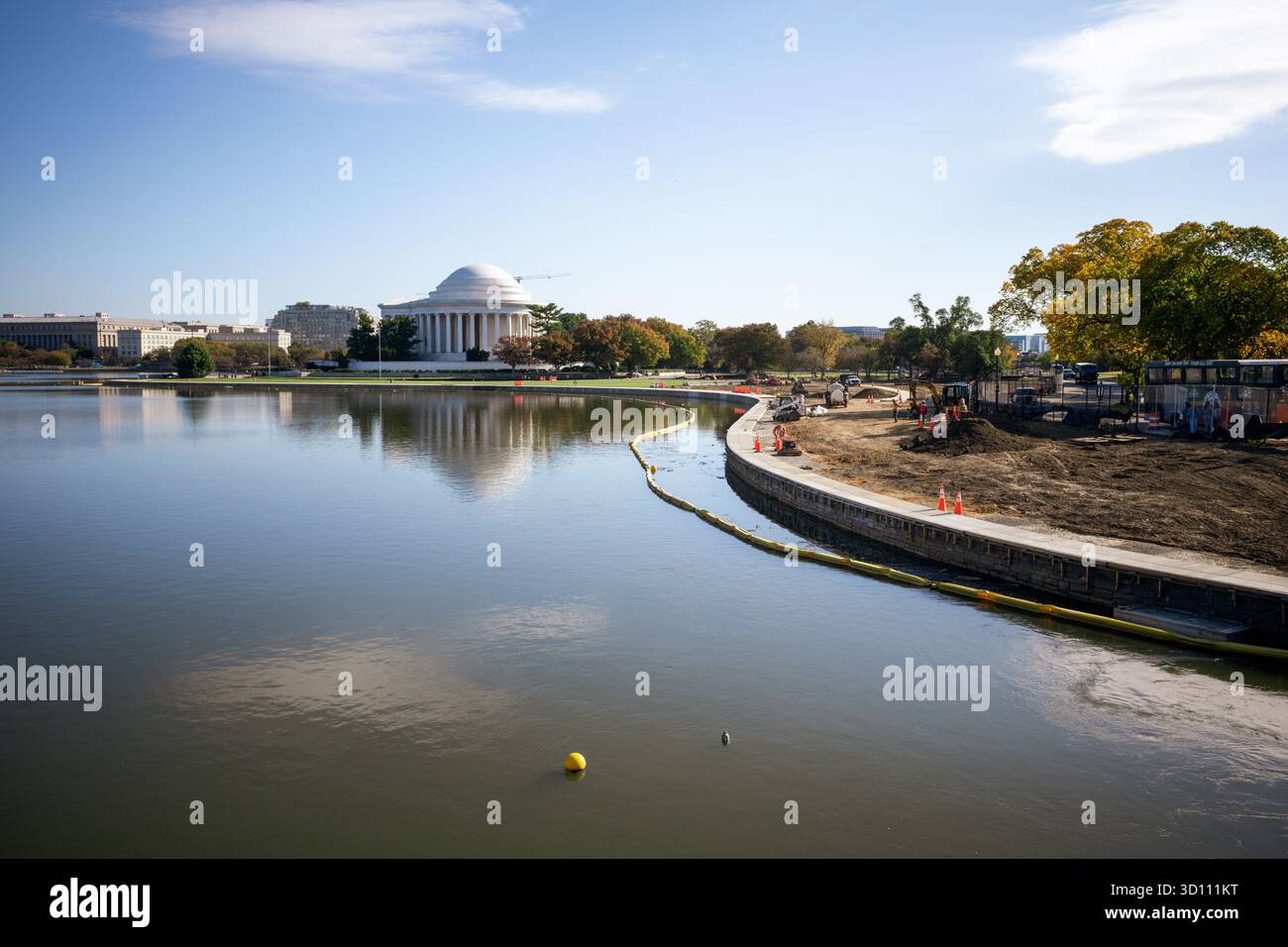 Tidal Basin Seawall Reconstruction Project Washington DC // WASHINGTON DC — i progressi nel Tidal Basin Seawall Reconstruction Project sono visibili il 24 ottobre 2025. Sono in corso lavori di costruzione lungo il bacino delle maree, con attrezzature pesanti e una barriera temporanea nell'acqua. Il progetto mira a ricostruire le dighe deteriorate e ad alzarne l'altezza per combattere le inondazioni mareali quotidiane e affrontare il cedimento. L'iconico Thomas Jefferson Memorial si riflette in modo prominente sull'acqua, a testimonianza del fatto che l'area storica è protetta da questa vitale iniziativa infrastrutturale. Foto Stock
