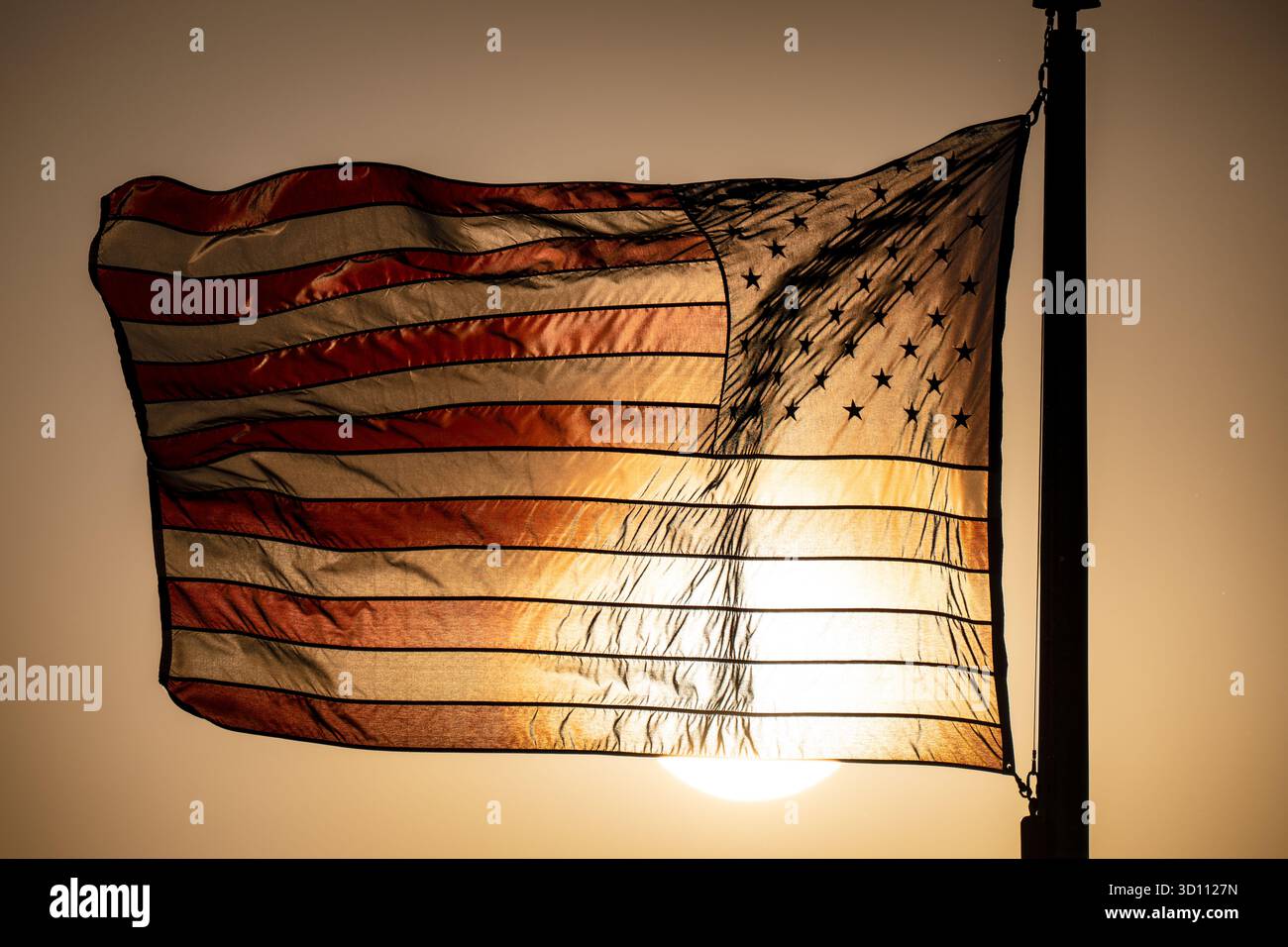 American Flag in Golden Hour Sunlight Washington DC // WASHINGTON DC - una bandiera americana vola da un'asta sul National Mall di Washington DC, illuminata dalla luce solare dell'ora d'oro. Questo importante simbolo degli Stati Uniti si trova vicino al monumento a Washington, un obelisco in onore di George Washington, il primo presidente degli Stati Uniti. Il monumento, completato nel 1884, è la struttura in pietra più alta del mondo e l'obelisco più alto, alto 169 metri (555 piedi). Rimane un punto di riferimento centrale nel Distretto di Columbia. Foto Stock