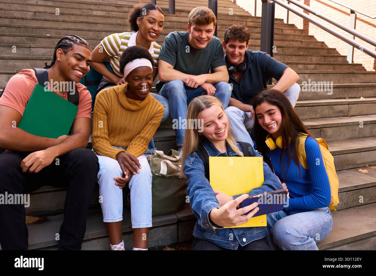 Gruppo di studenti diversi che si fanno selfie sulle scale dell'università Foto Stock