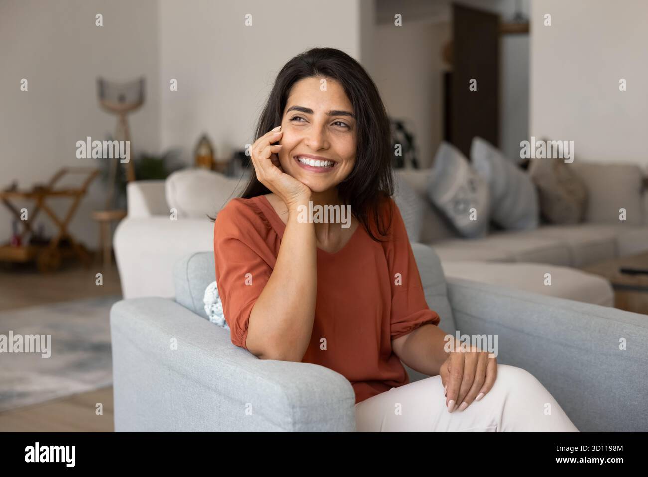 Felice giovane donna ispanica padrona di casa che si diverte a stare in una casa accogliente Foto Stock