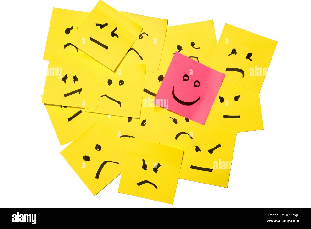 15 carte gialle ammucchiate di facce tratteggiate che esprimono rabbia o tristezza, di fronte ad una carta rosa con un volto che esprime felicità Foto Stock