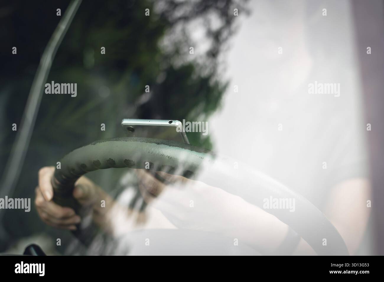 Donna che usa lo smartphone in un'auto, concetto di guida pericolosa Foto Stock