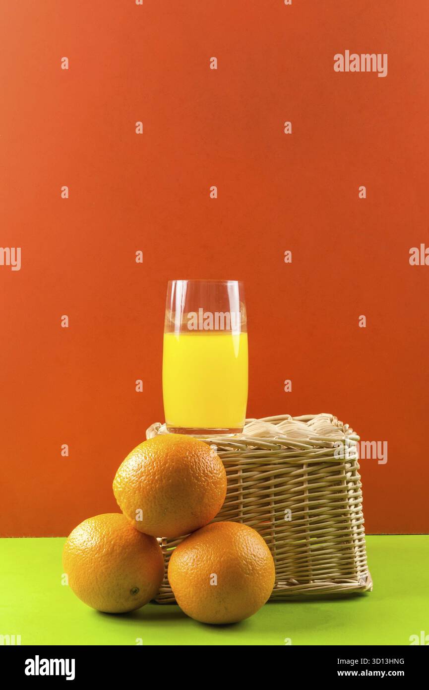 Bicchiere di succo con arance su sfondo rosso Foto Stock