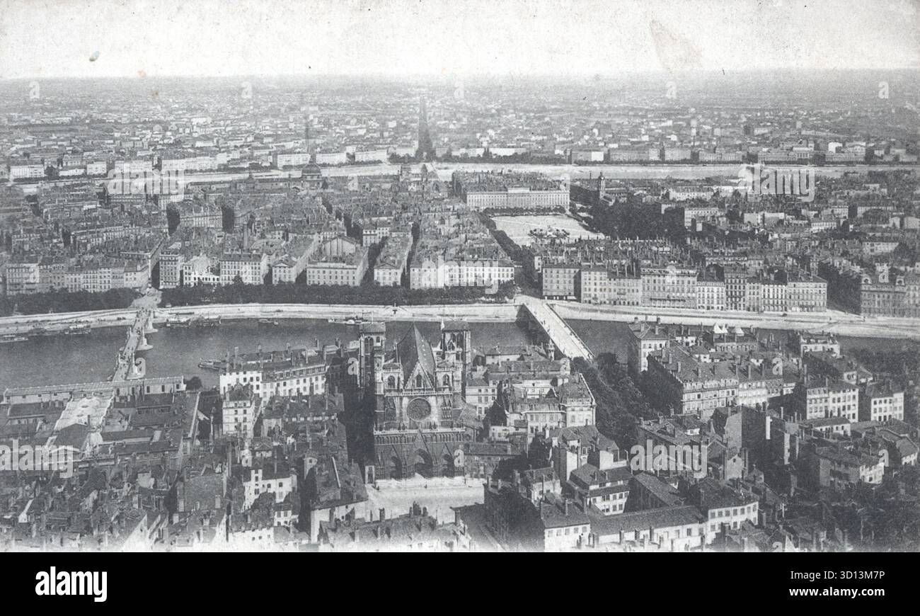 Una vista aerea di Lione rivela un fitto paesaggio urbano attraversato dai fiumi Rhône e Saône, con ponti che collegano i quartieri storici della città. Una struttura simile a una cattedrale fissa il primo piano, mentre i tetti si allungano verso l'orizzonte. Pubblicata intorno al 1920 da Léon Lévy, questa cartolina cattura il ritmo architettonico e la grandezza civica di Lione all'inizio del XX secolo. Da una cartolina originale. Foto Stock