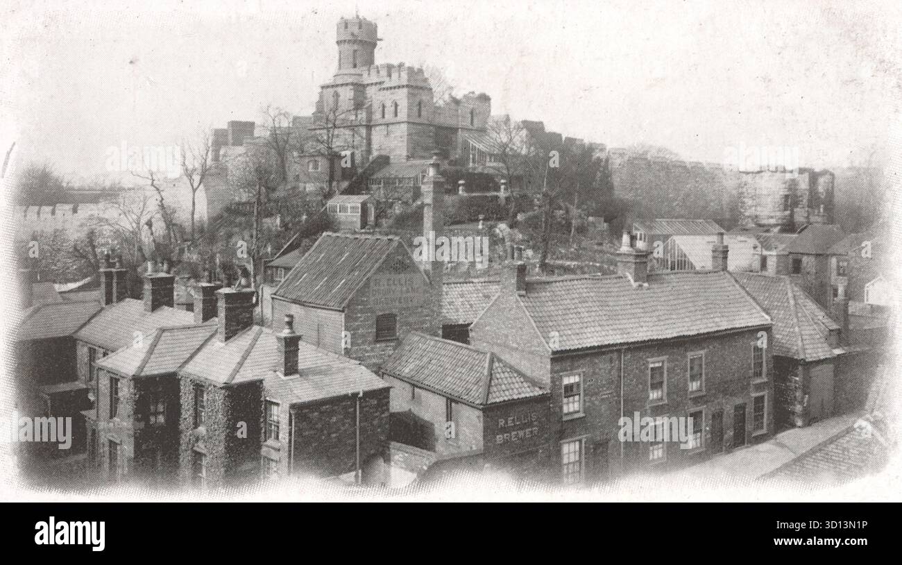Una fotografia dai toni seppia cattura una vista alta delle mura medievali del Castello di Lincoln e della Torre di osservazione in cima a una ripida collina. Sotto le fortificazioni, un gruppo di tetti appartenenti a edifici della classe operaia o commerciali forma il primo piano. L'immagine sottolinea la drammatica altezza del castello e il contrasto urbano storico di Lincoln. Da una cartolina originale pubblicata da Boots come parte della loro Pelham Series, c1910. Foto Stock
