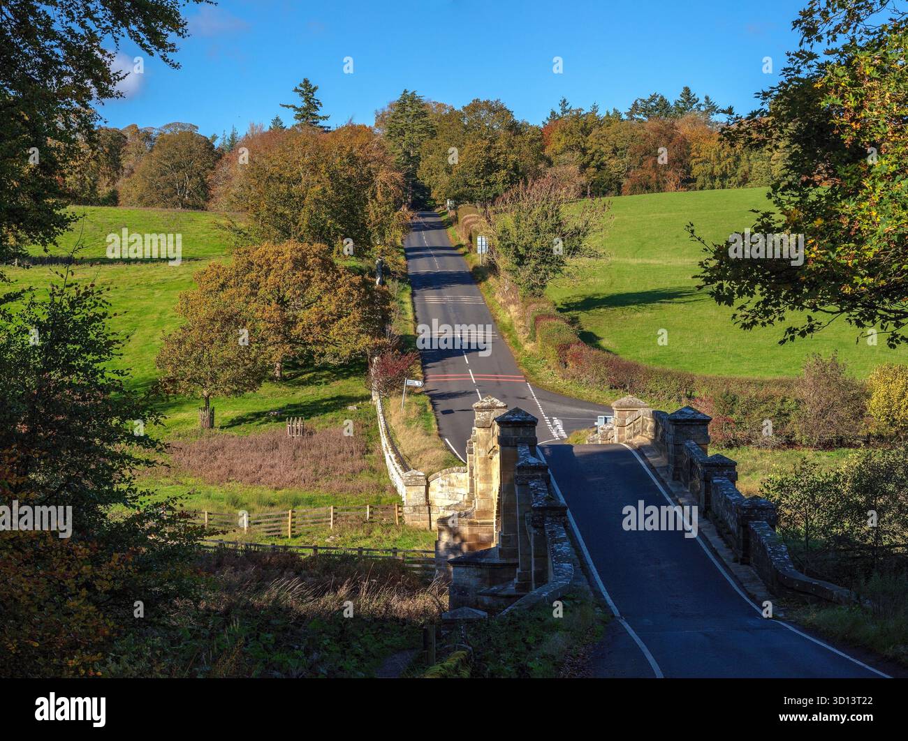 Una vista in una giornata d'autunno soleggiata del Paine's Bridge e della turnpike Road sul fiume Wansbeck sulla Wallington Hall Estate nel Northumberland vicino Cambo Foto Stock