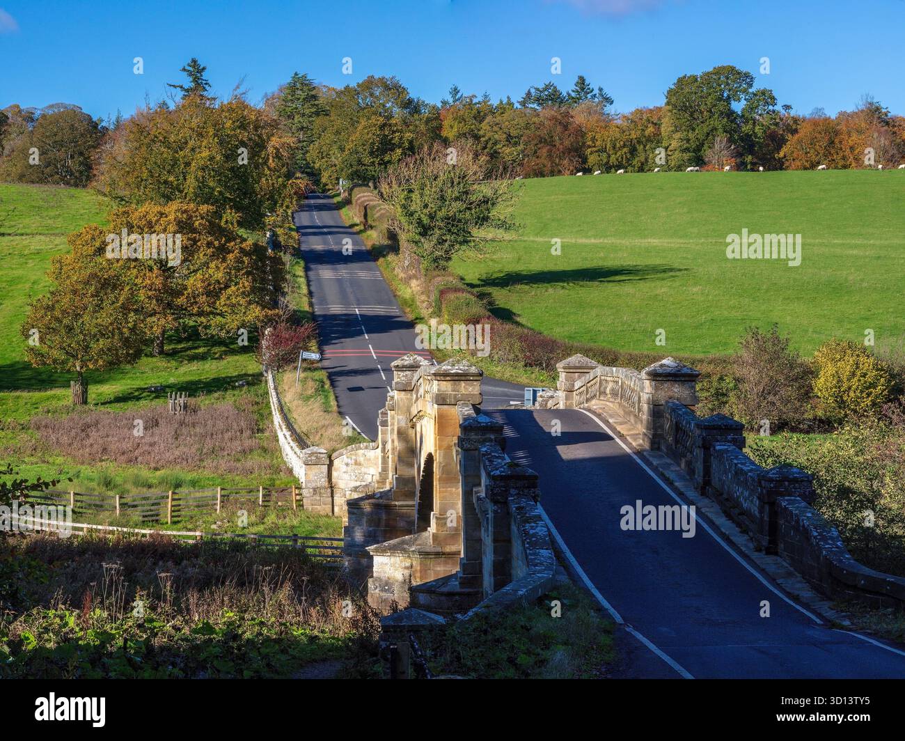 Una vista in una giornata d'autunno soleggiata del Paine's Bridge e della turnpike Road sul fiume Wansbeck sulla Wallington Hall Estate nel Northumberland vicino Cambo Foto Stock