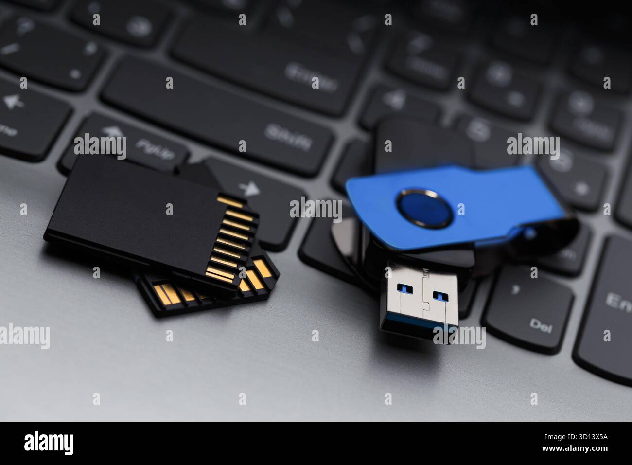 Primo piano di un'unità flash USB e di una scheda di memoria SD accanto alla tastiera di un computer laptop. Сoncept per il trasferimento dei dati, il backup e l'archiviazione digitale Foto Stock