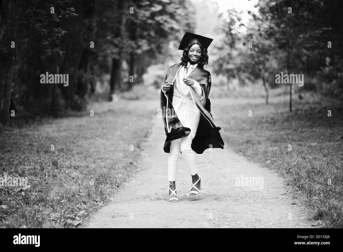 Felice bella africano nero ragazza americana con hat e camice laureati Foto Stock