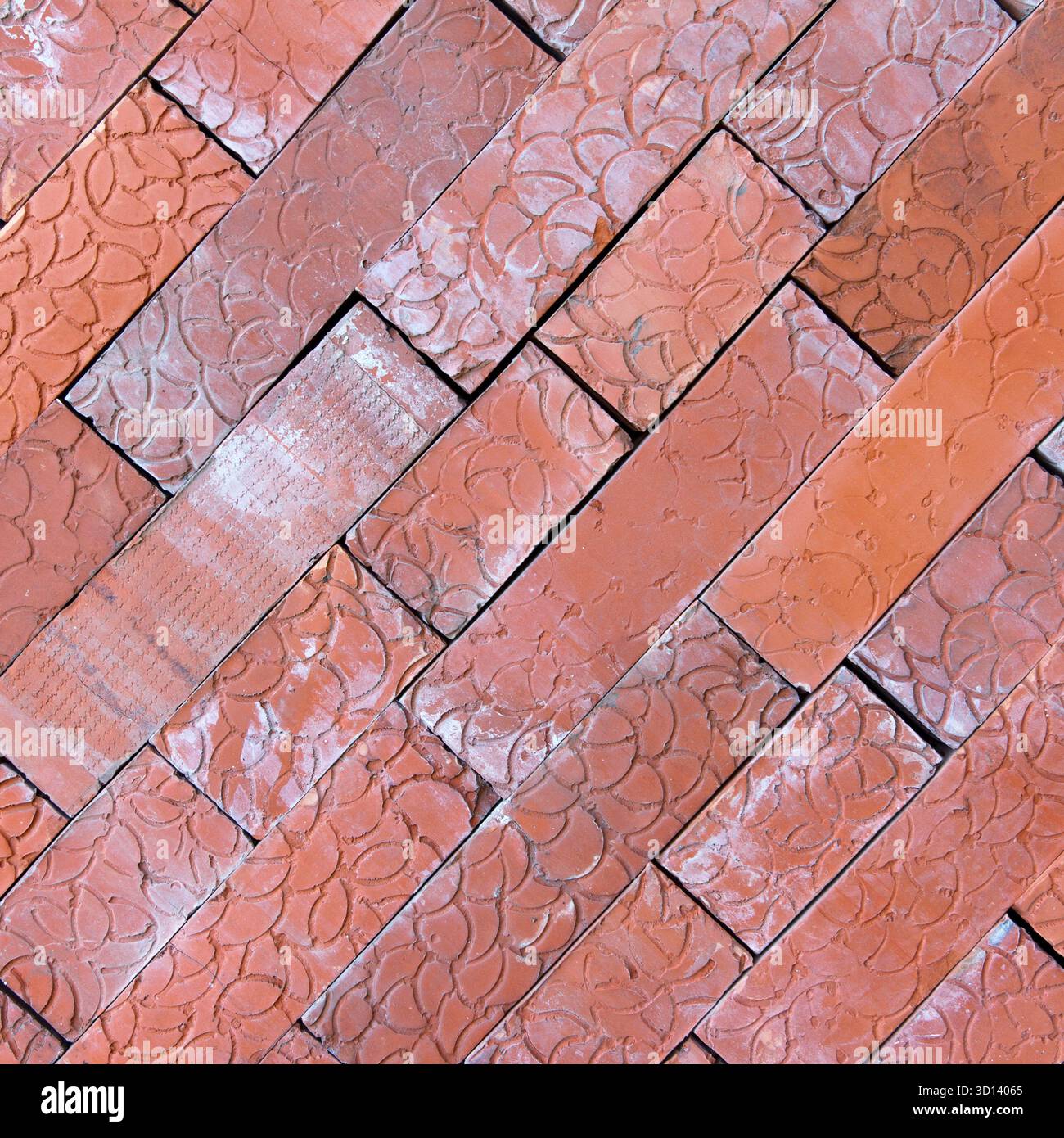 Vista ravvicinata di un motivo a spina di pesce fatto di mattoni rossi. I mattoni sono disposti in diagonale, mostrando la loro consistenza e le loro variazioni di colore Foto Stock