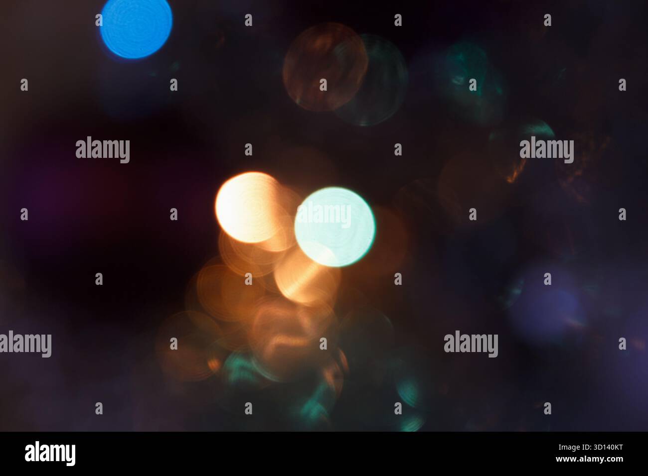 Luci bokeh astratte in vari colori, creando uno sfondo morbido e sognante. La scenografia presenta forme circolari sfocate nelle tonalità blu, arancione e verde Foto Stock