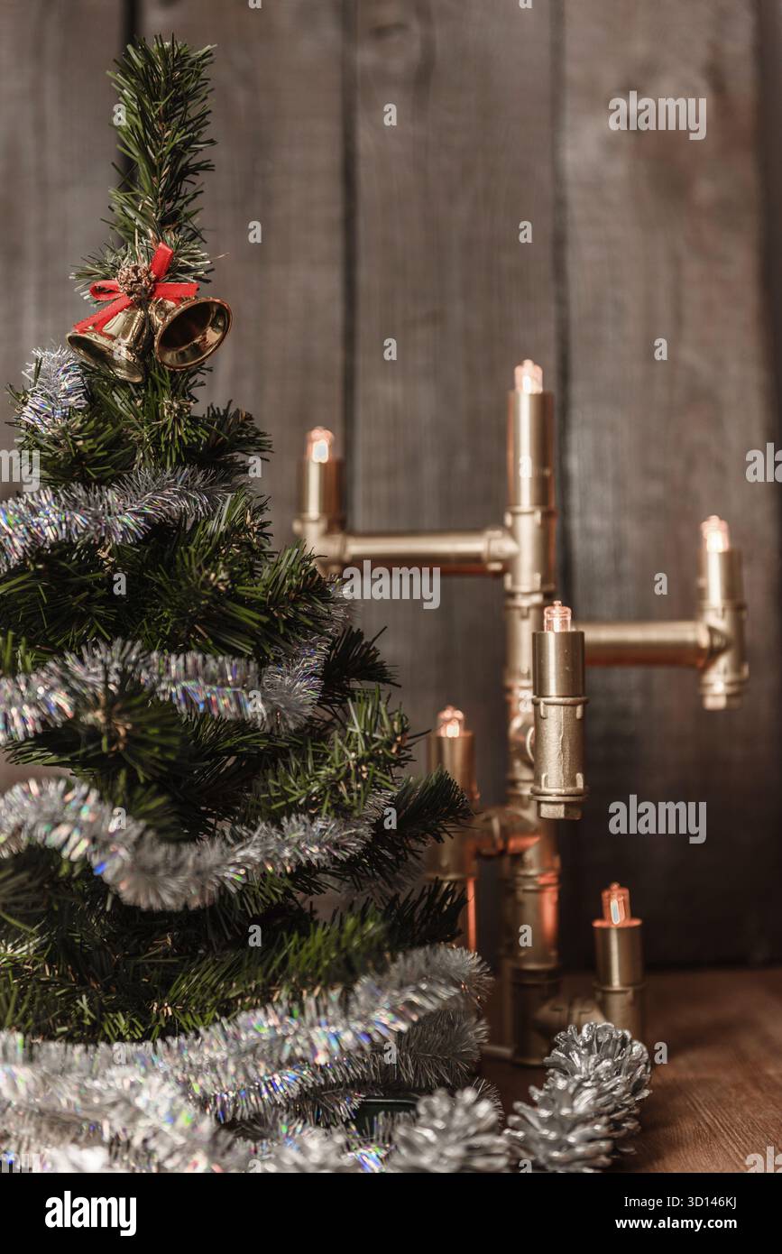 Natale albero decorativo è adornata con la pioggia si erge sul tavolo con una lampada accesa luci Foto Stock