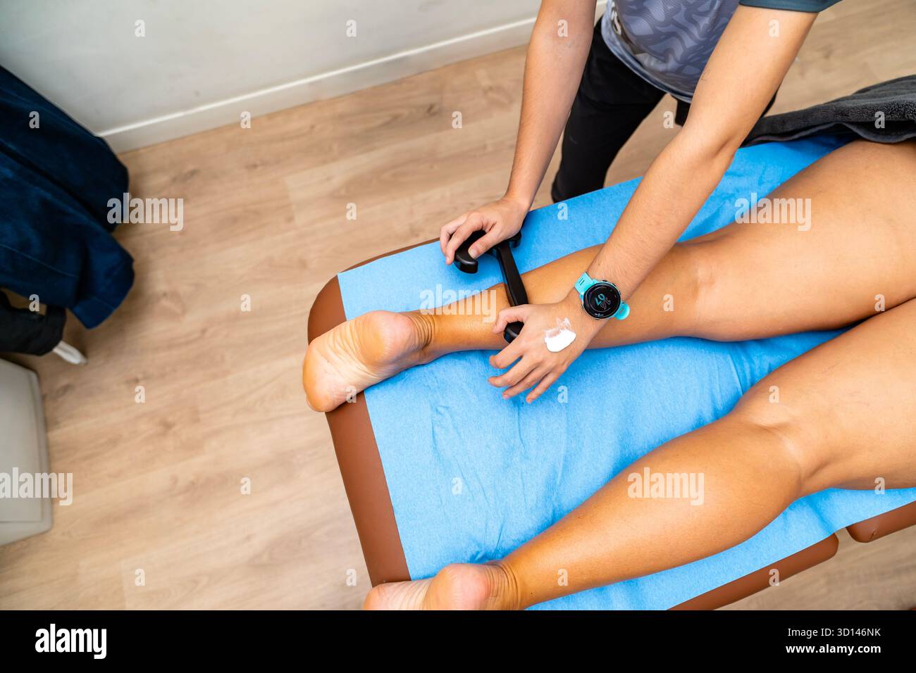 Fisioterapista che applica la mobilizzazione dei tessuti molli assistita dallo strumento alla gamba del paziente Foto Stock