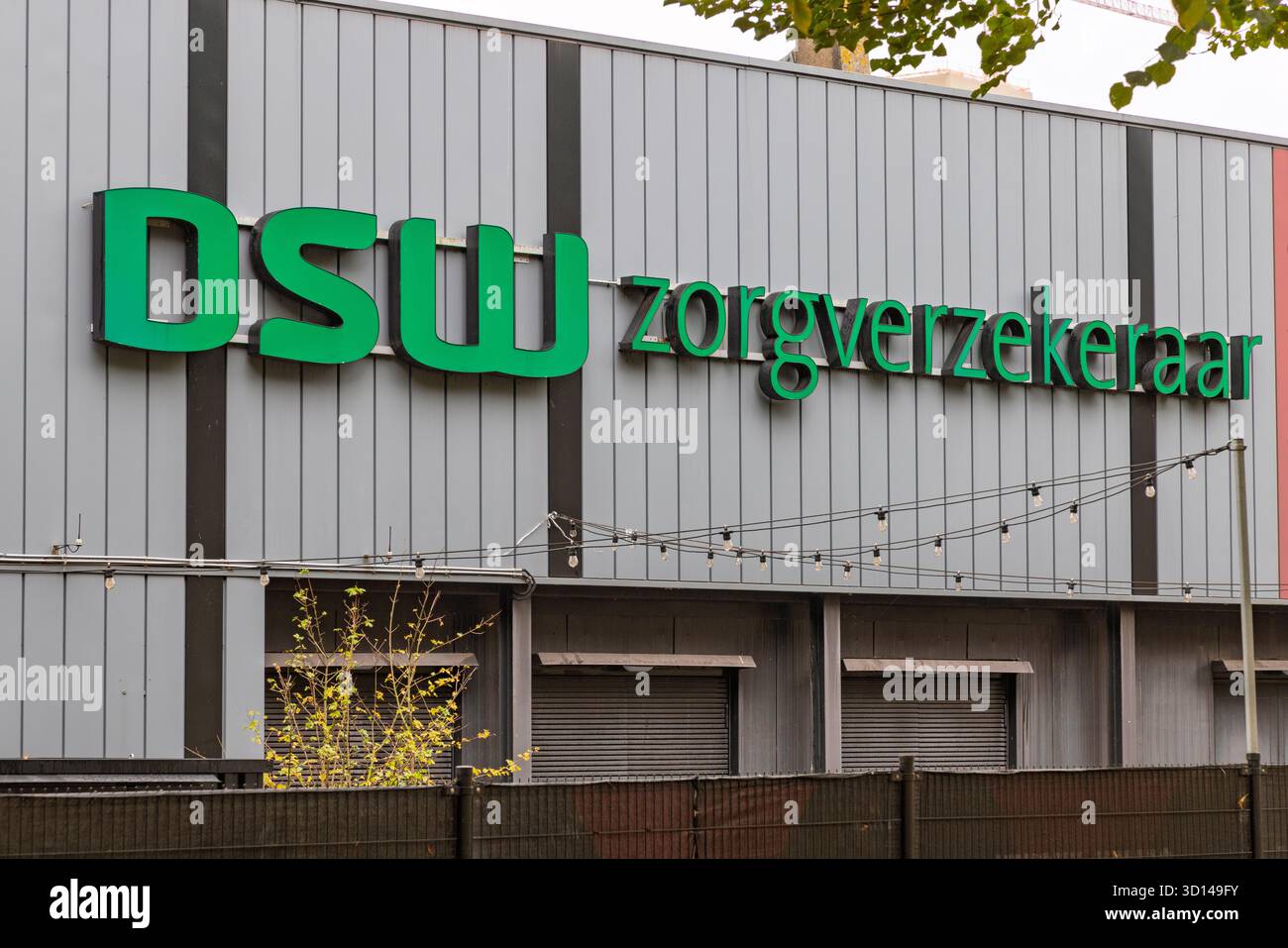 Segnaletica esterna della DSW Zorgverzekeraar (assicurazione sanitaria) con un grande logo verde sulla facciata grigia in metallo ondulato dell'edificio dell'azienda. Rotore Foto Stock
