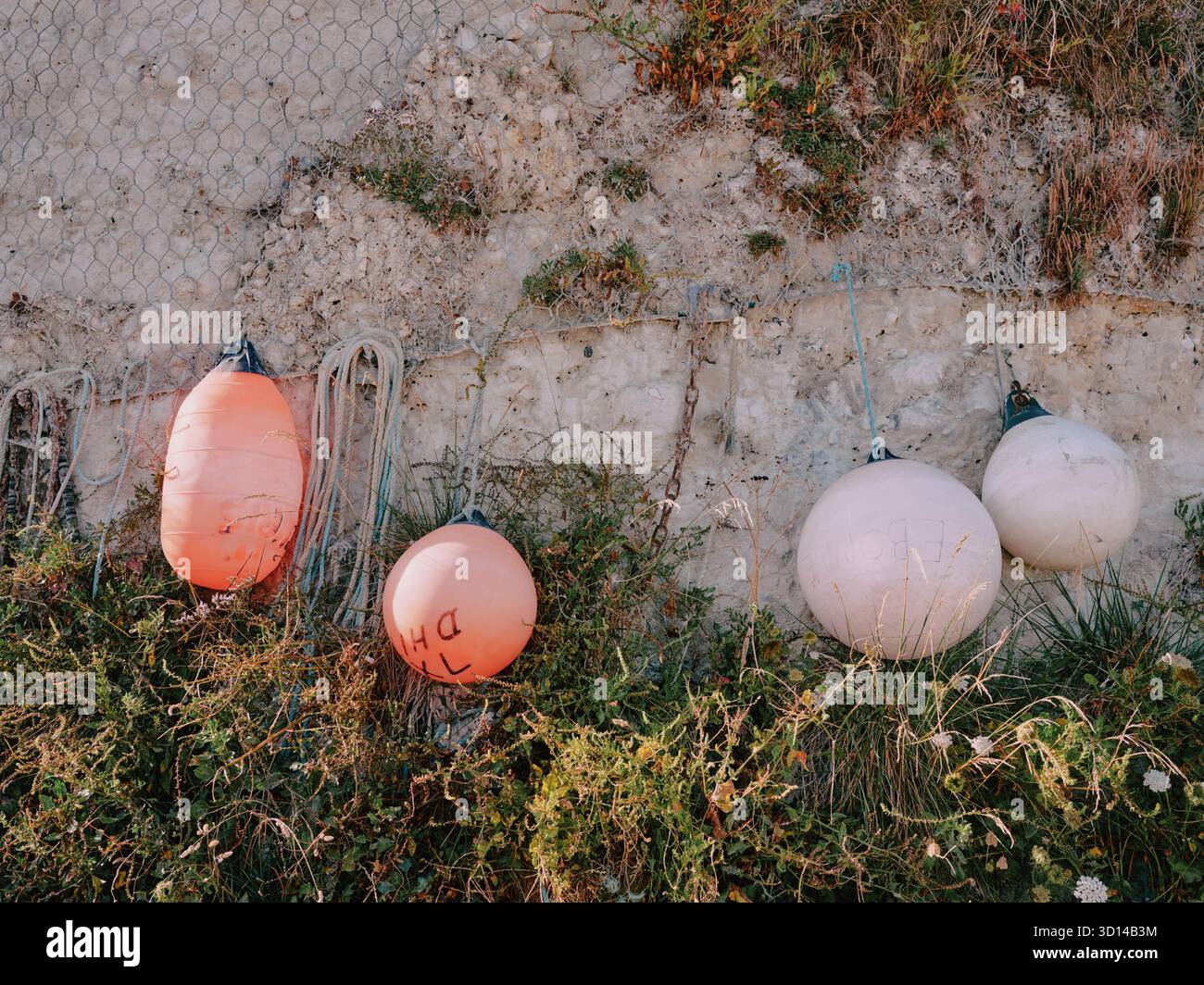 Parafanghi per barche da pesca collocati su una parete rocciosa di gesso Foto Stock