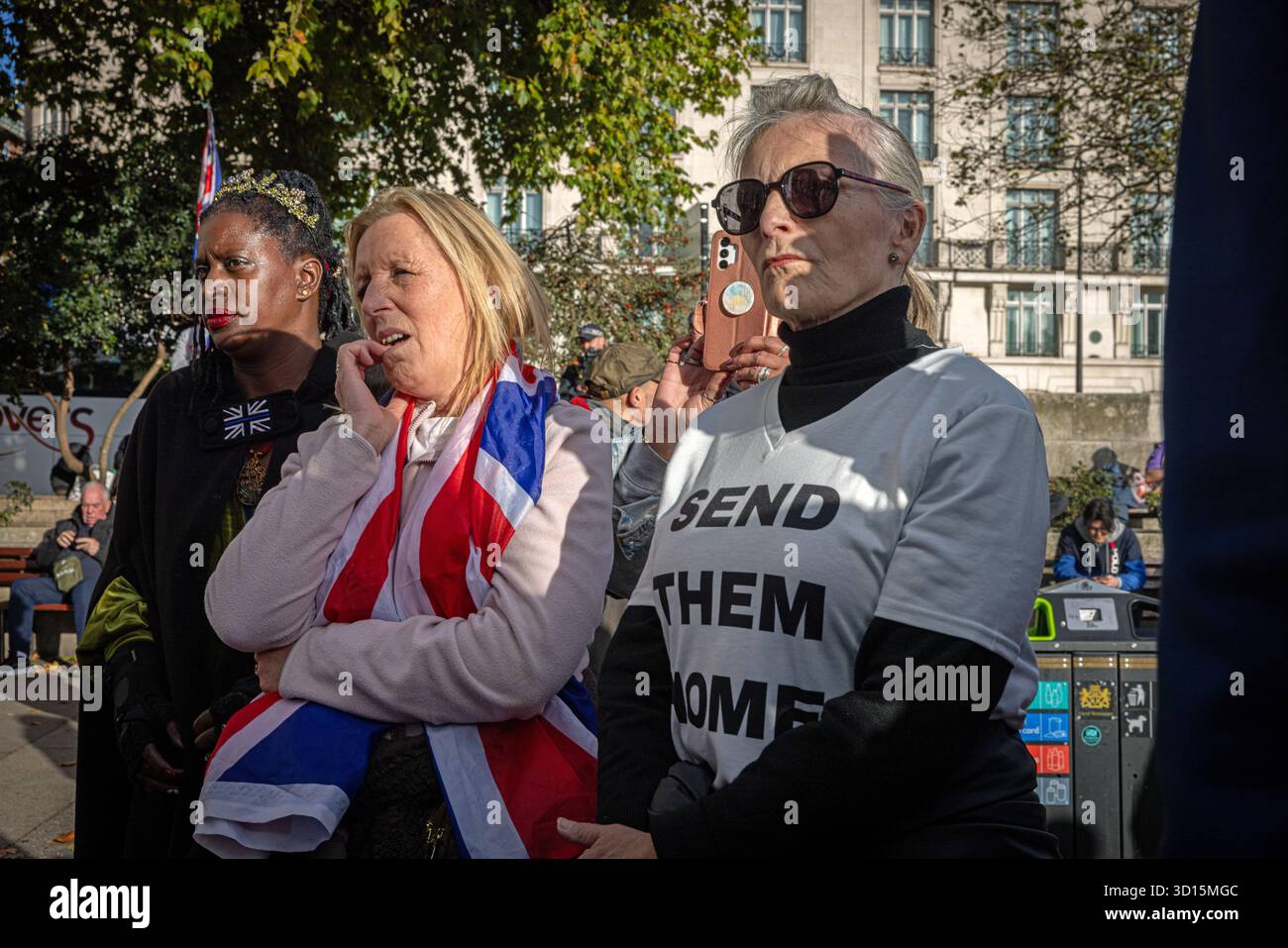 Una folla diversificata di sostenitori di estrema destra, tra cui una donna nera e una donna bianca si riuniscono in una manifestazione politica all'aperto a Londra. Foto Stock