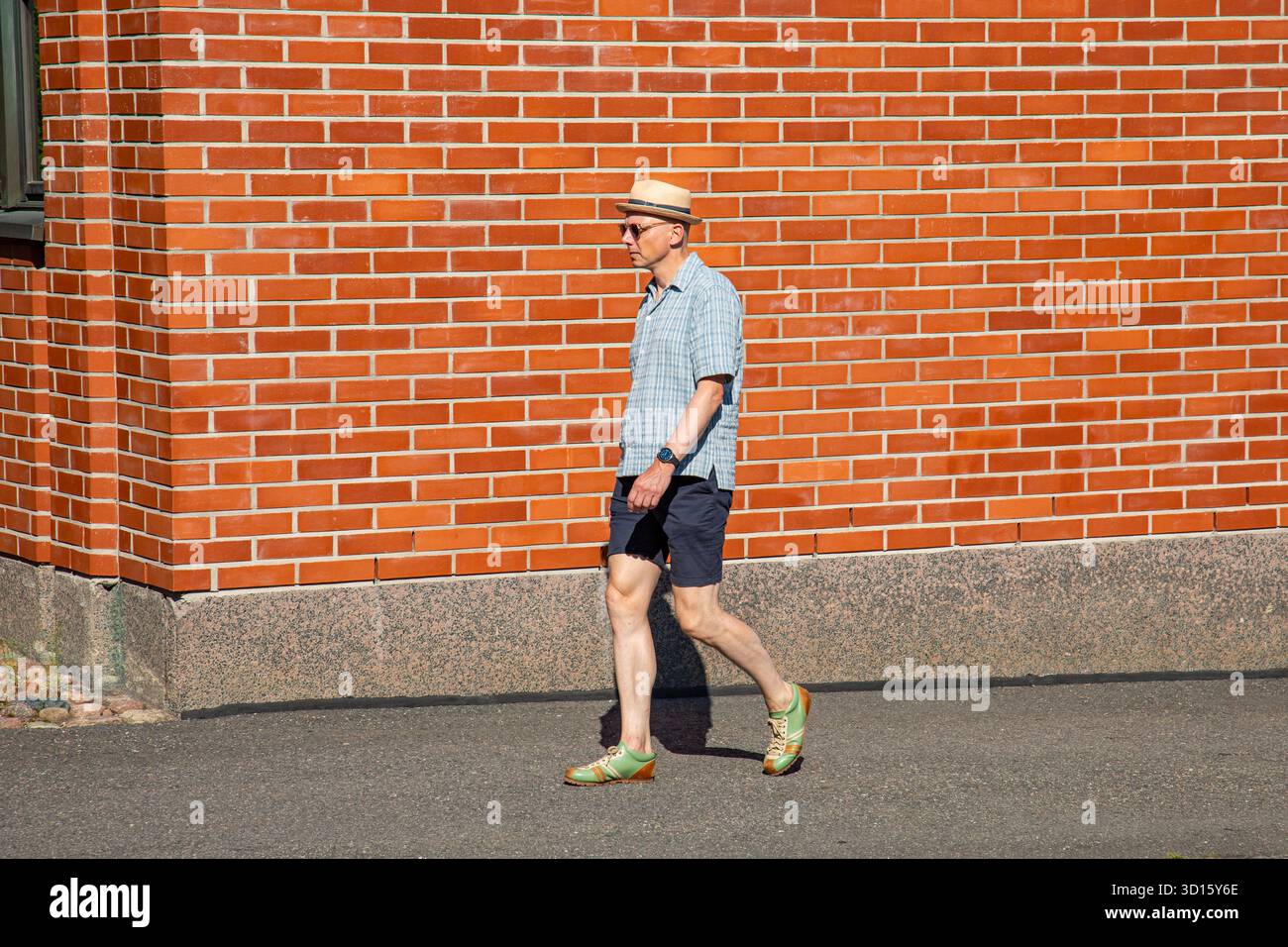 Uomo che passeggia con Ensi Linja vestito con abiti estivi nel quartiere Kallio di Helsinki, Finlandia Foto Stock