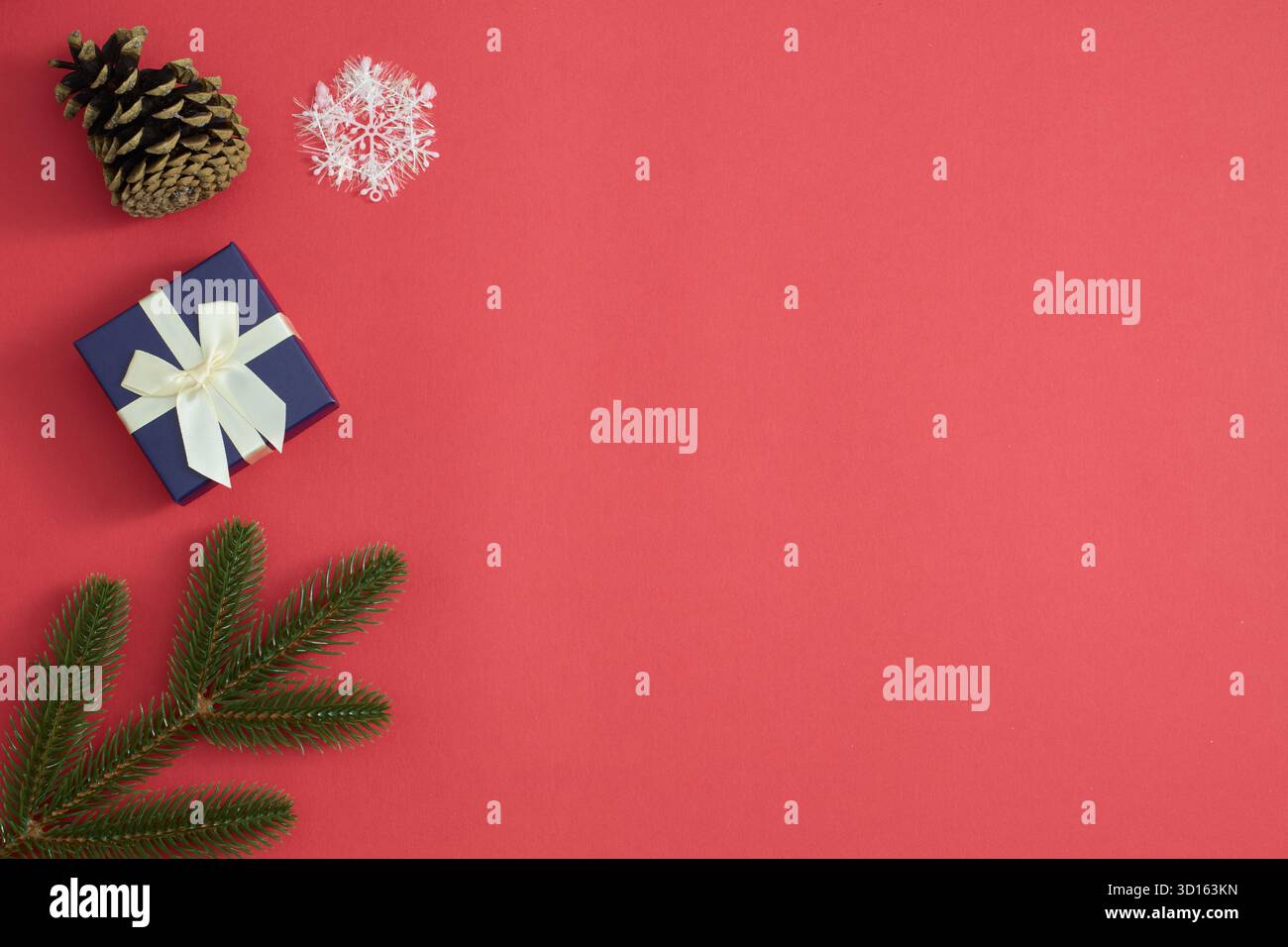 Confezione regalo, rami di abete rosso, fiocchi di neve su sfondo rosso festivo Foto Stock