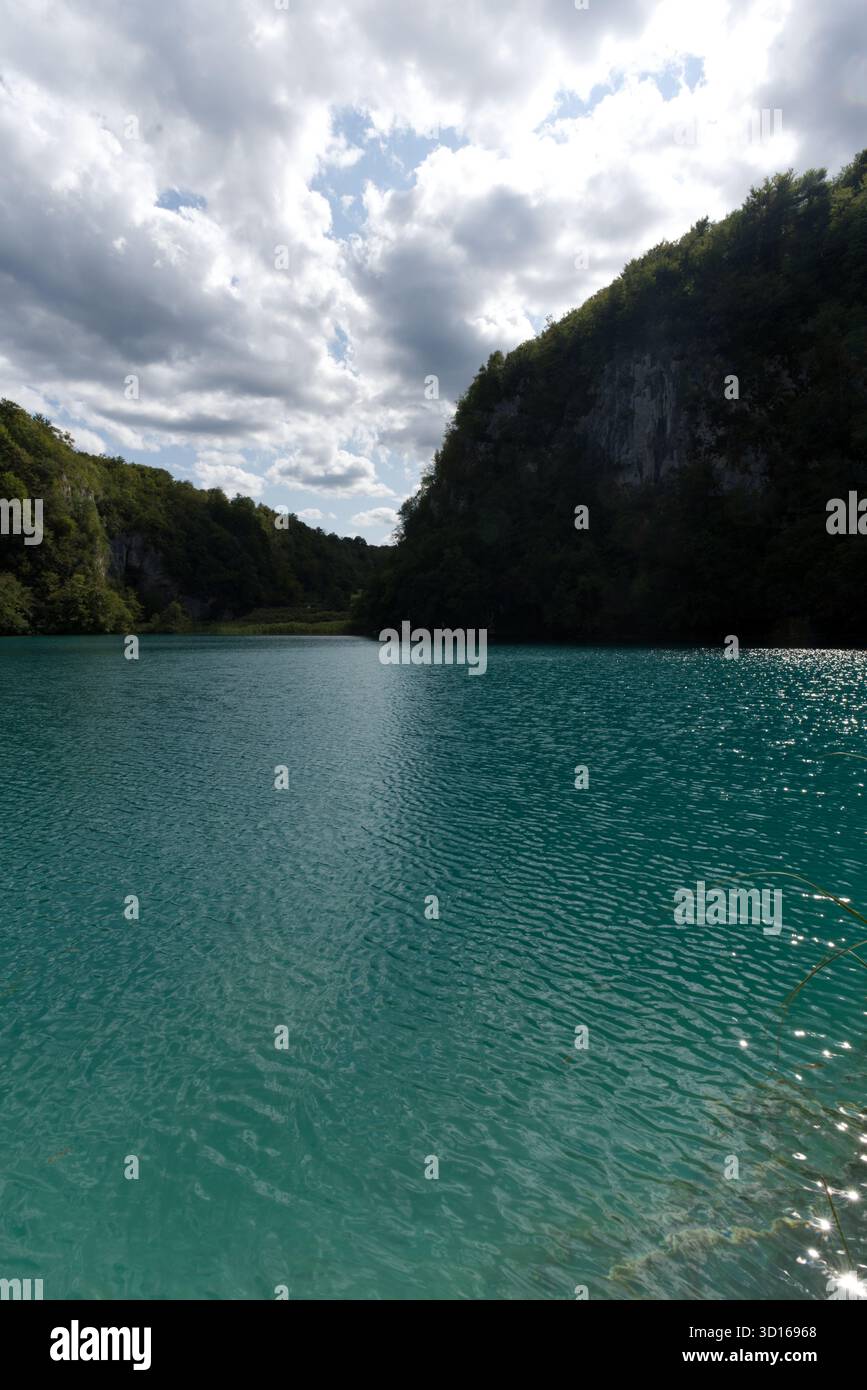 Un lago turchese incastonato tra le colline boscose della Croazia, Plitvice affascina con cascate, scogliere calcaree e sereni riflessi. Foto Stock