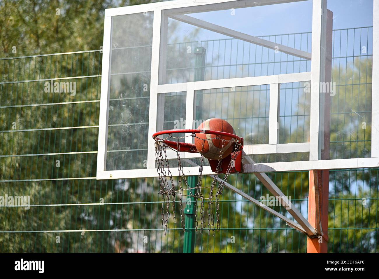 Primo piano tiro palla da basket arancione nel cesto in campo all'aperto, angolo basso, vista frontale Foto Stock