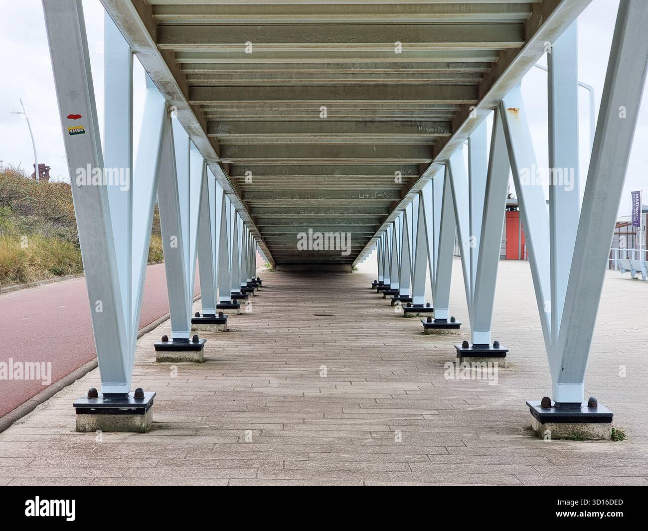 Vista simmetrica sotto il ponte in legno con travi di supporto geometriche in metallo triangolari, a Scheveningen, Paesi Bassi - Immagine stock catturata con smartphone