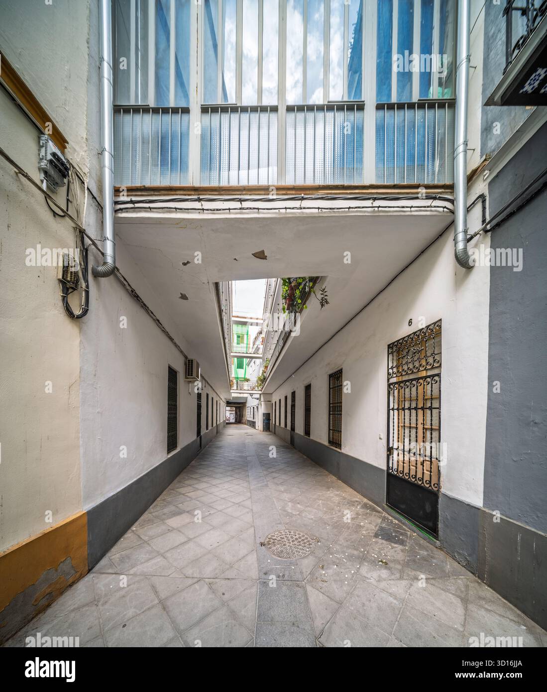 Pasaje Valvanera: Corridoio residenziale progettato nel 1915 da Manuel Martín, con pavimentazione piastrellata e gallerie sopraelevate che collegano abitazioni modeste a Sevil Foto Stock