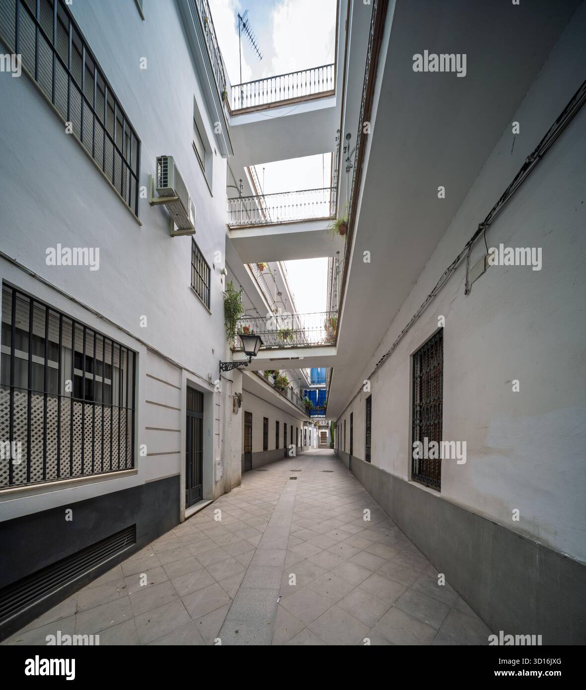 Pasaje Valvanera: Corridoio residenziale progettato nel 1915 da Manuel Martín, con pavimentazione piastrellata e gallerie sopraelevate che collegano abitazioni modeste a Sevil Foto Stock