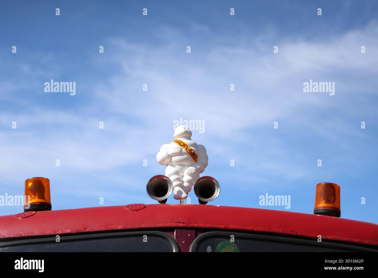 Uomo Michelin in cima a un veicolo d'epoca con luci di emergenza e avvisatori acustici Foto Stock