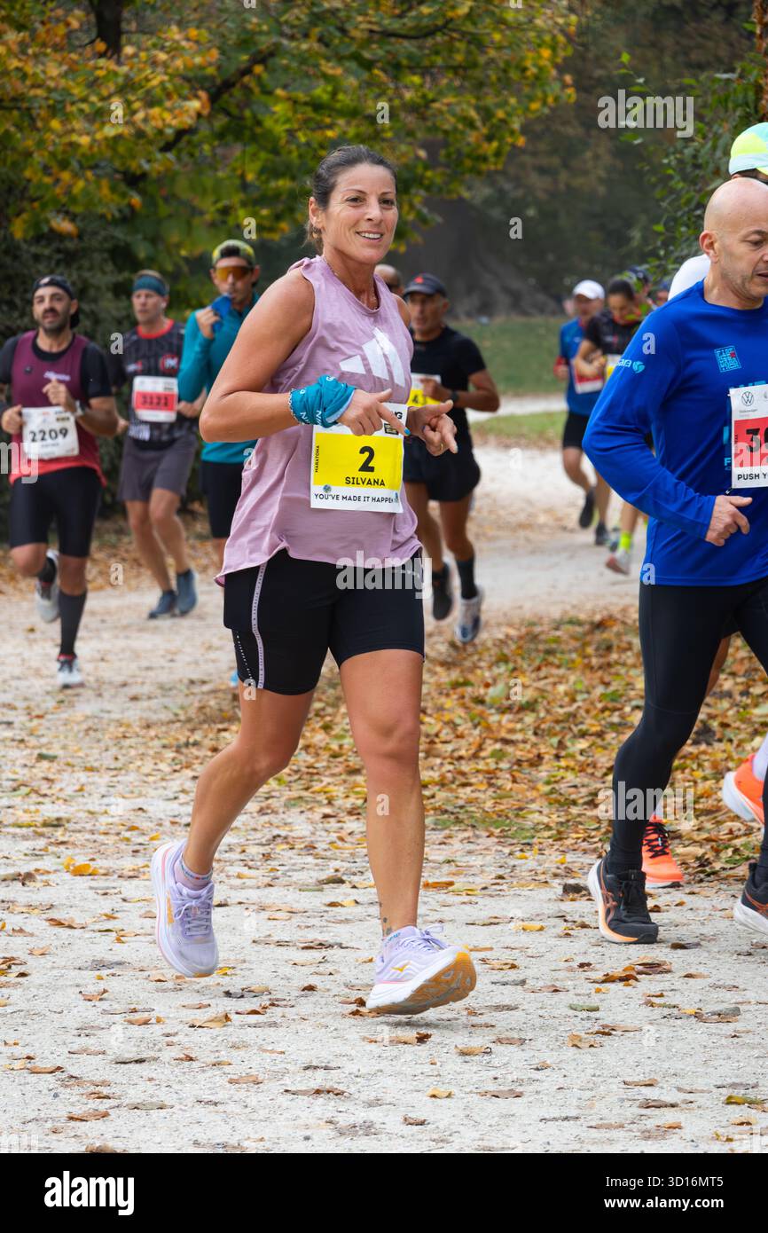 I partecipanti alla maratona corrono attraverso il panoramico parco autunnale mostrando energia resistenza e lavoro di squadra in un evento sportivo all'aperto di stile di vita sano. Foto Stock