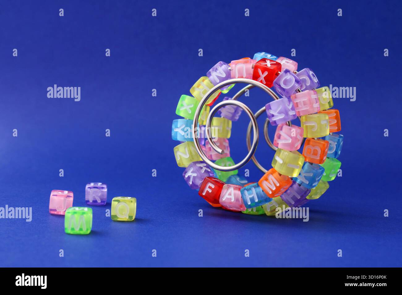 Cubi colorati con lettere su una spirale metallica, curva di apprendimento Foto Stock
