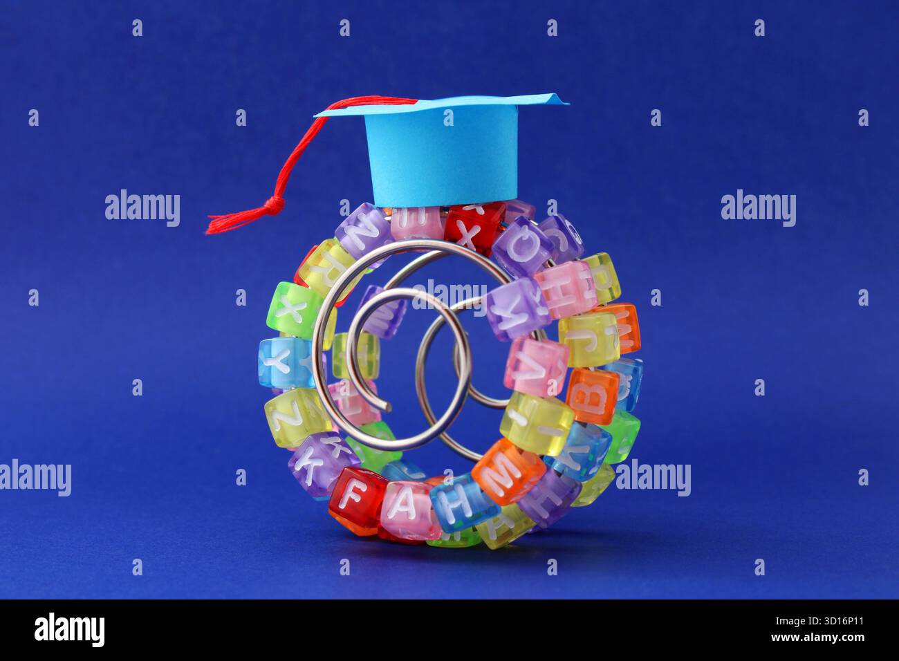 Cappello graduato su una curva di apprendimento, cubi colorati con lettere in una spirale metallica Foto Stock