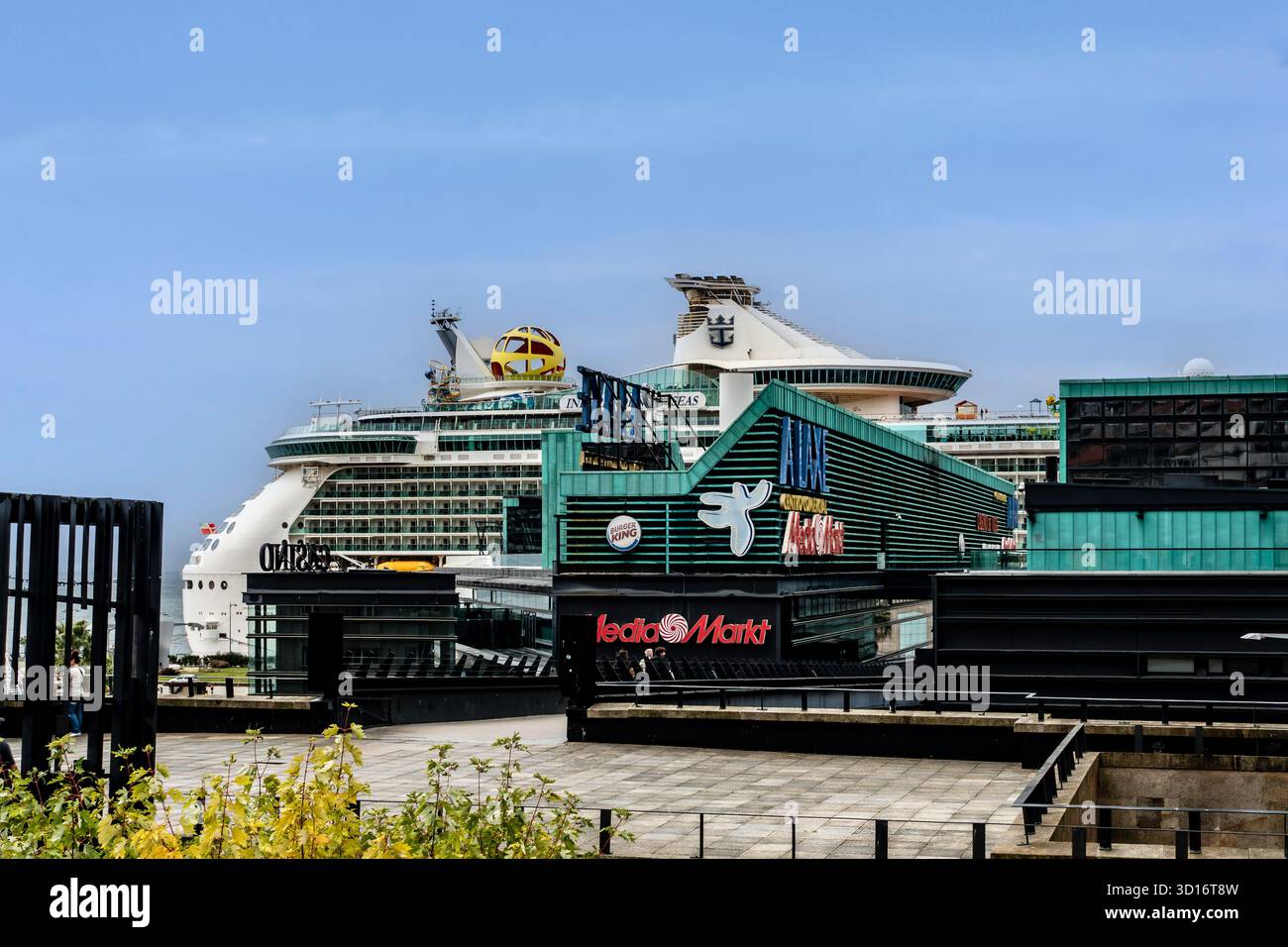 Nave da crociera ormeggiata accanto A Un centro commerciale Laxe con MediaMarkt a Vigo, Galizia, Spagna, che mette in evidenza turismo, vendita al dettaglio, e viaggi marittimi. Foto Stock