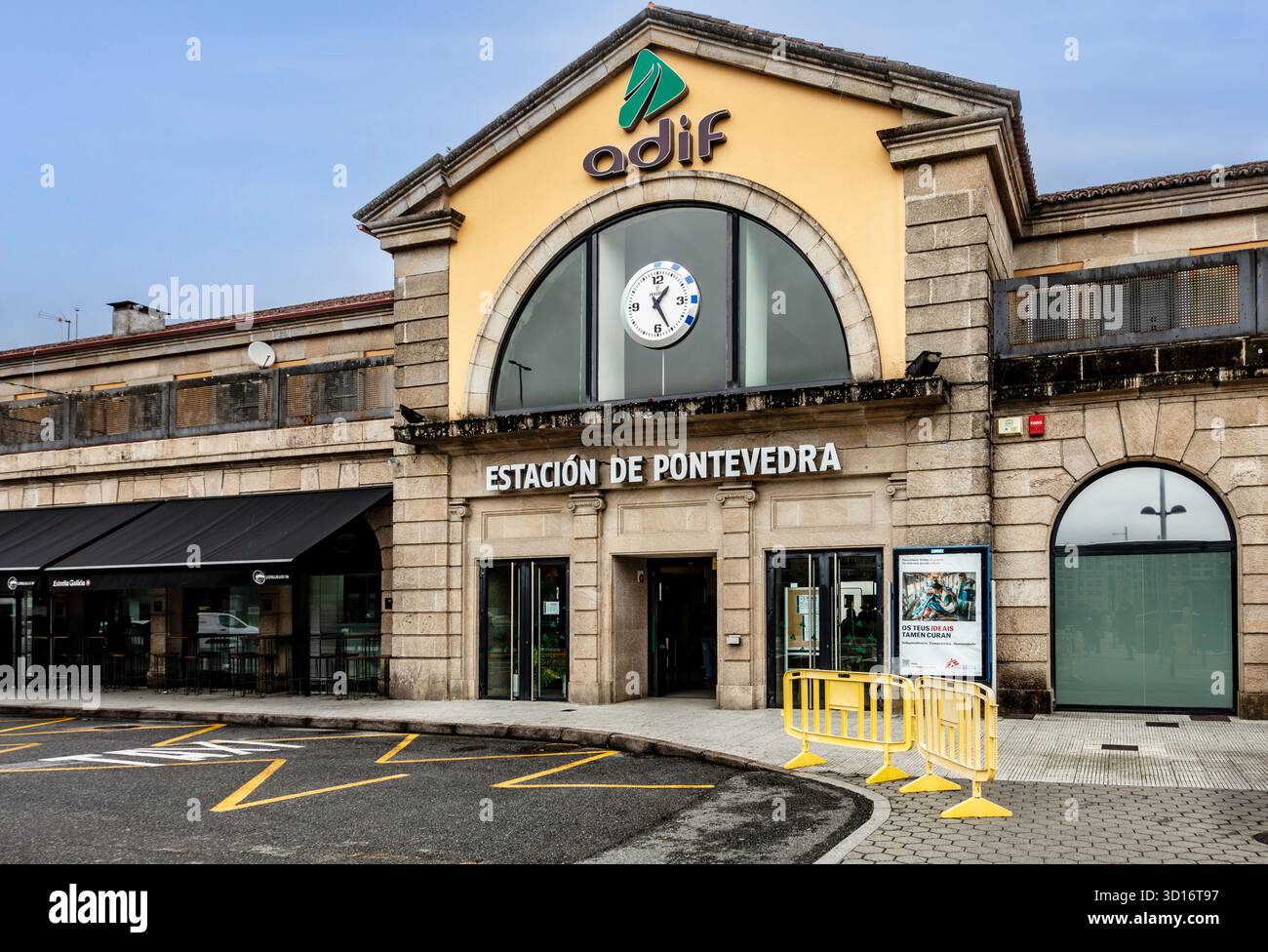 Facciata della stazione ferroviaria ADIF di Pontevedra, Spagna, con orologio, segnaletica e architettura in pietra sotto un cielo limpido. Foto Stock