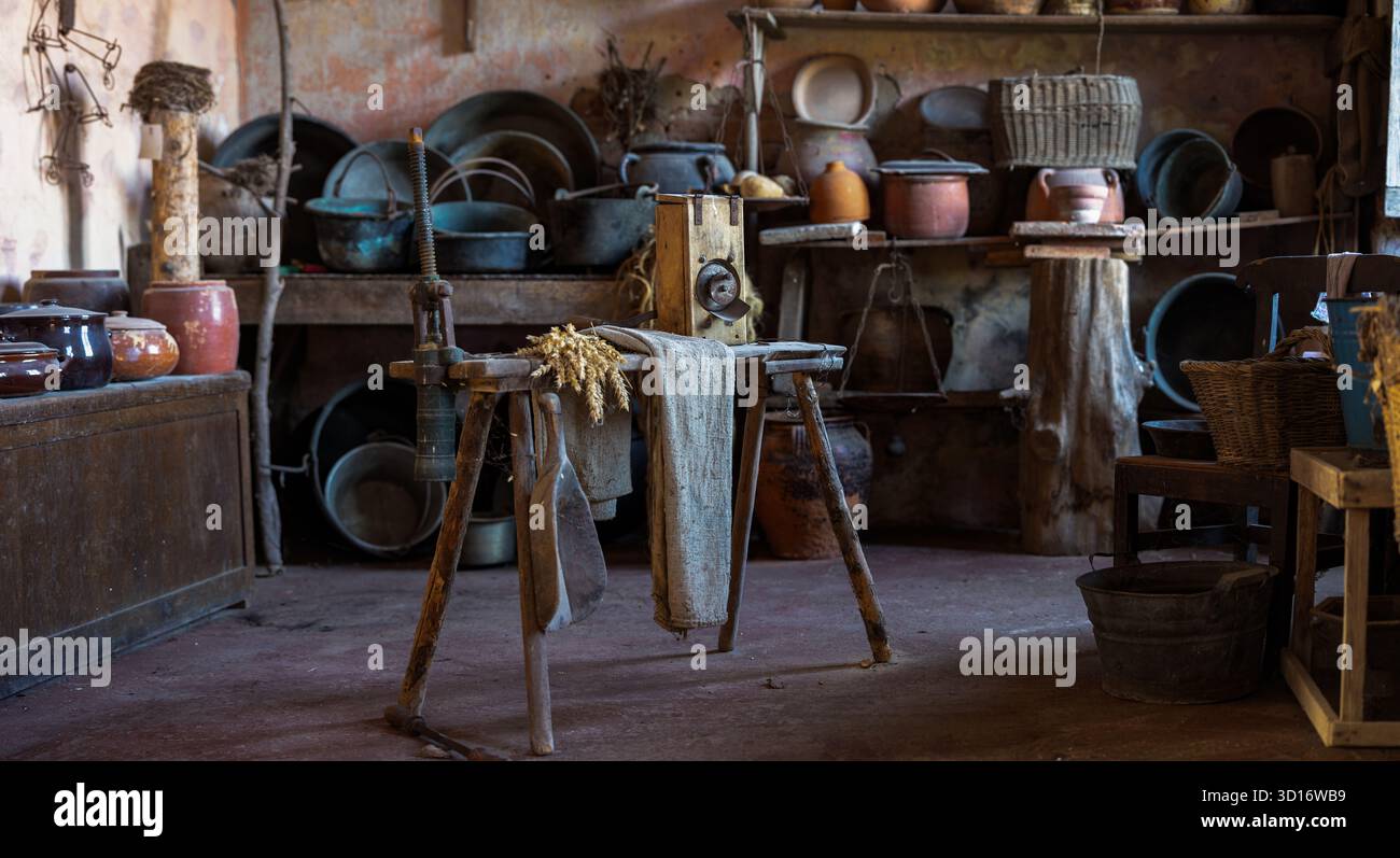 Interno in cucina rustica vintage con ceramiche tradizionali e utensili agricoli antichi su un tavolo in legno Foto Stock