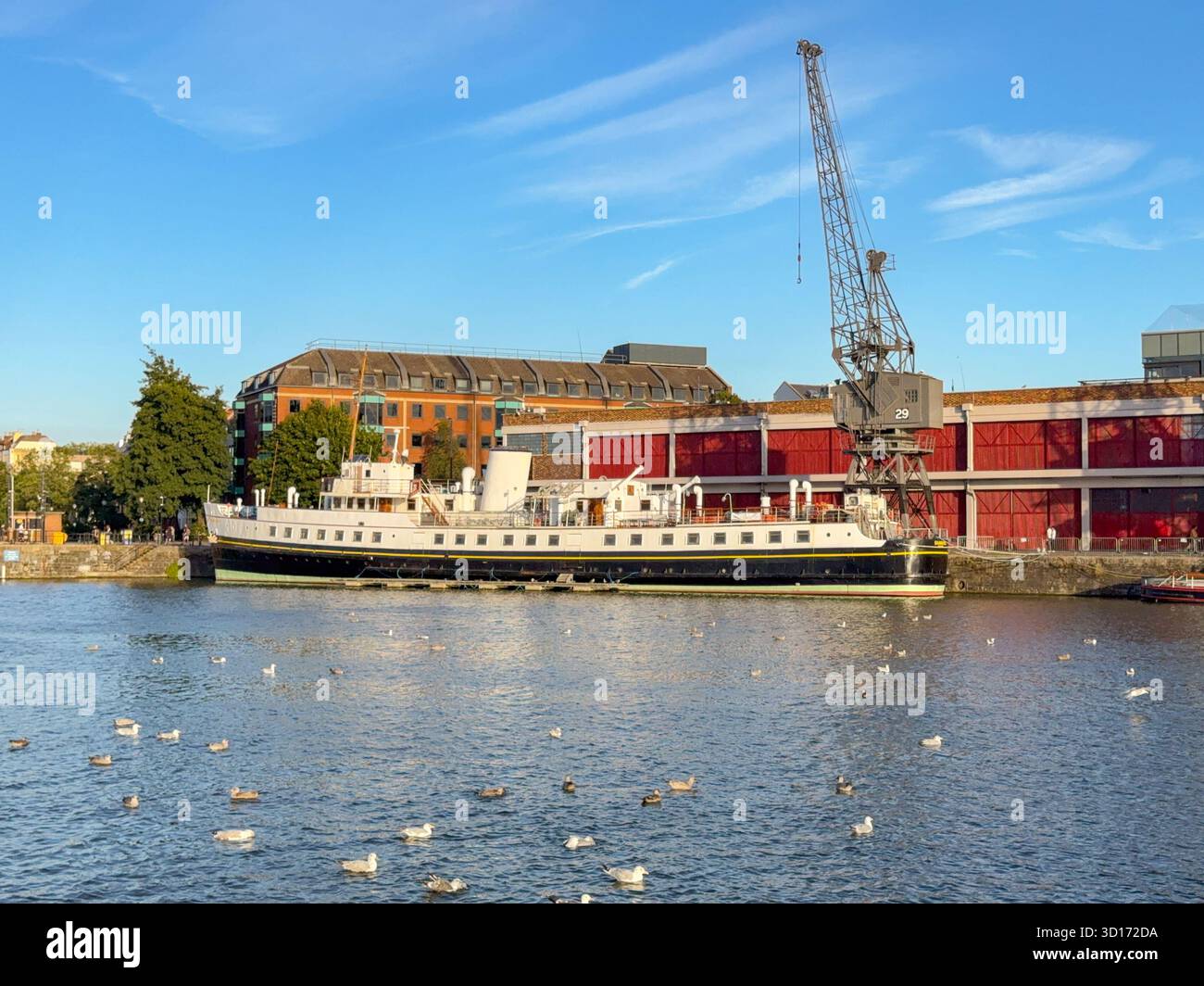 Bristol, Avon, Inghilterra, Regno Unito - 25 aprile 2025: Vista panoramica di una vecchia gru sul porto e nave a vapore d'epoca nell'area dei moli di Bristol - Immagine stock catturata con smartphone