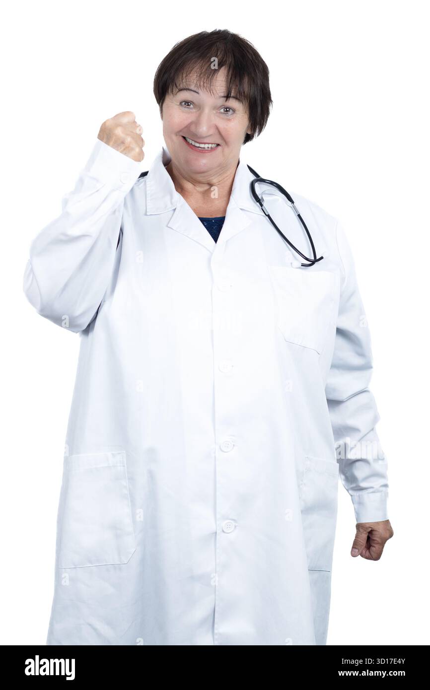 Donna anziana che indossa un camice da laboratorio e uno stetoscopio, sorridendo e stringendo il pugno in un gesto di trionfo, rappresentando il successo Foto Stock