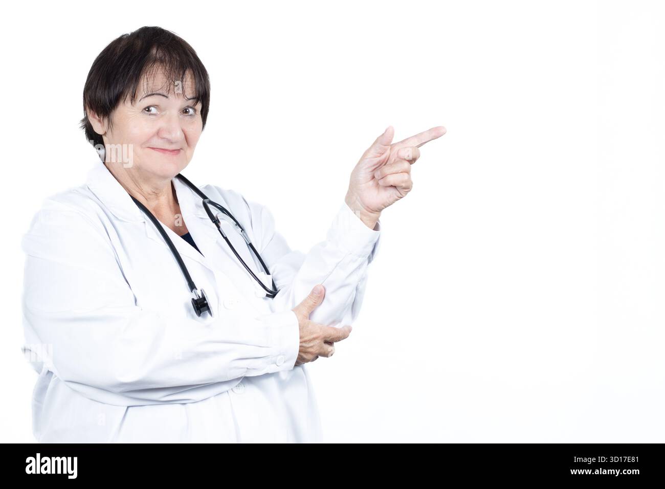 Medico donna anziana che indossa un cappotto bianco e stetoscopio, sorridente e che punta a destra, mostrando e raccomandando medico Foto Stock